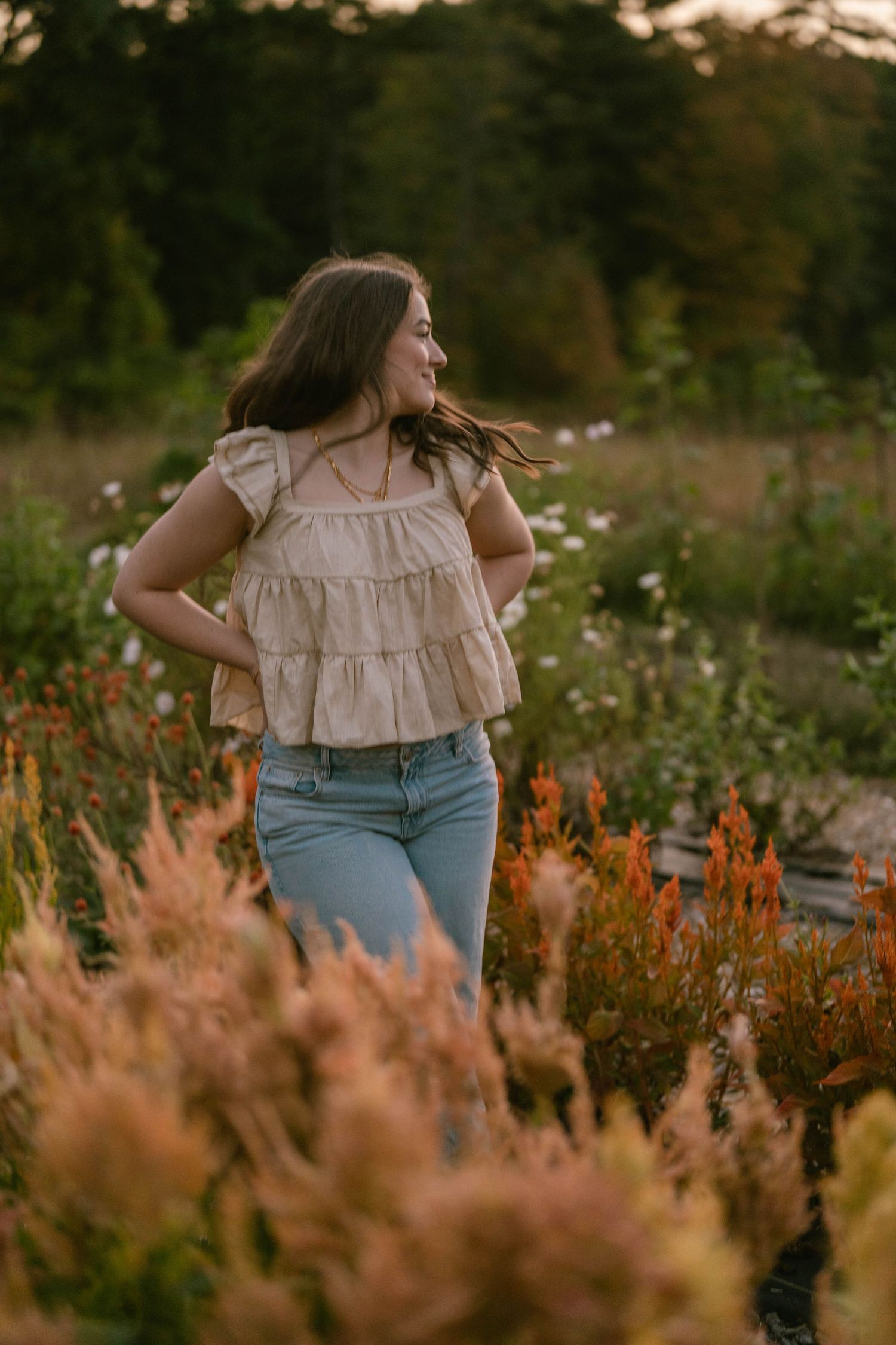 Teen strolling through tall flowers, casual and joyful senior photo.