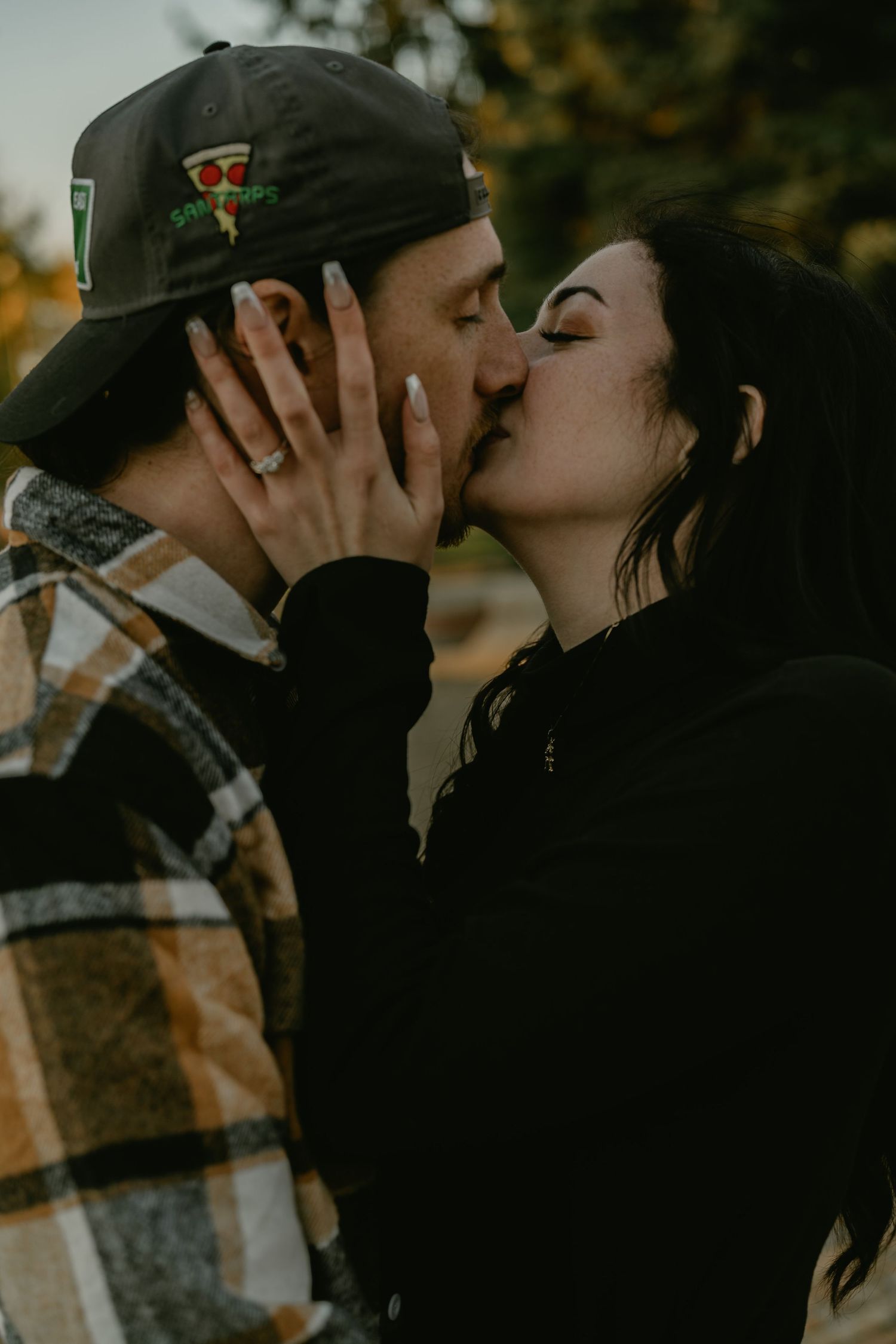 An intimate moment captured between two people wearing baseball caps in moody lighting.