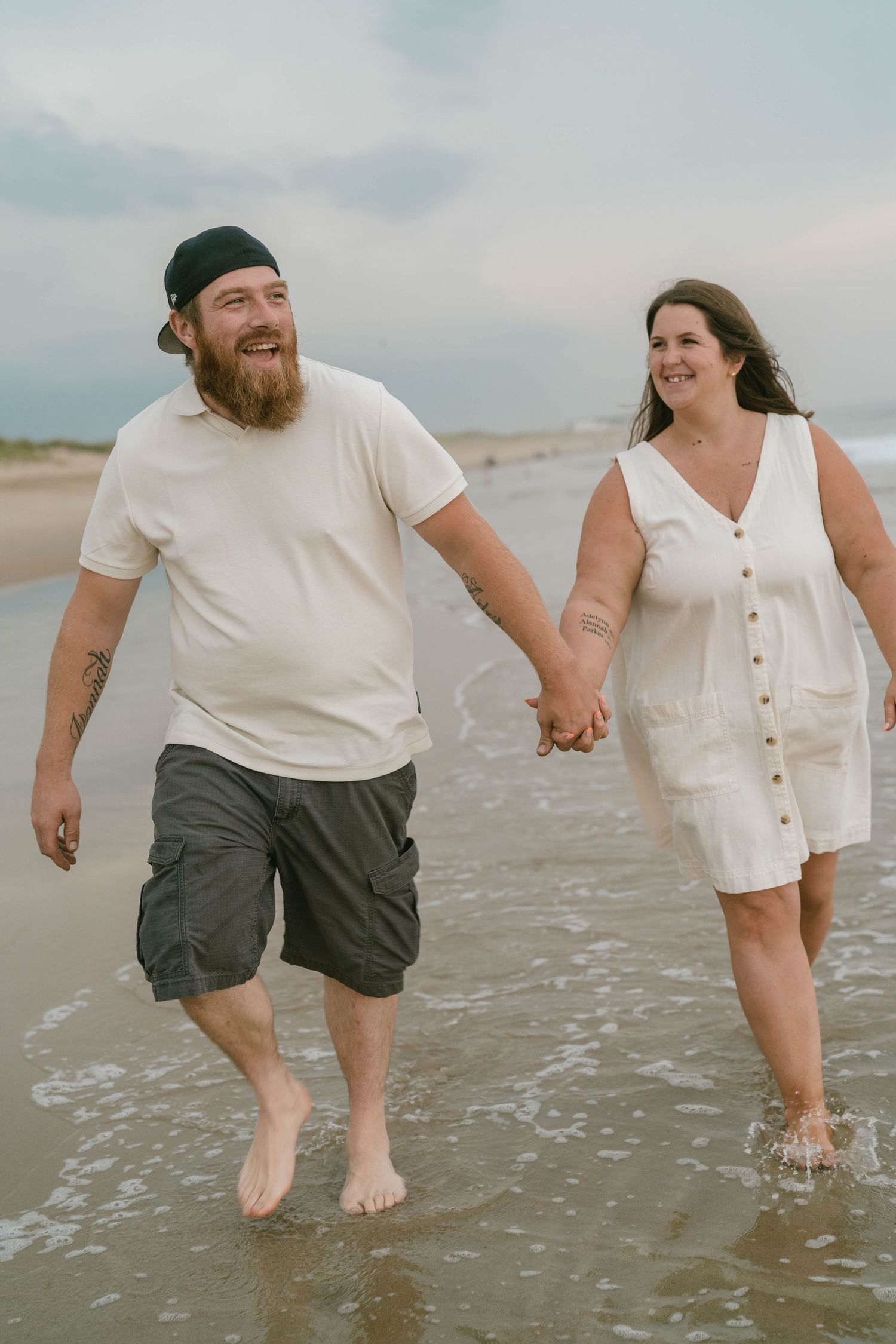 Romantic beach session with couple strolling on sand, smiling and enjoying golden hour together.