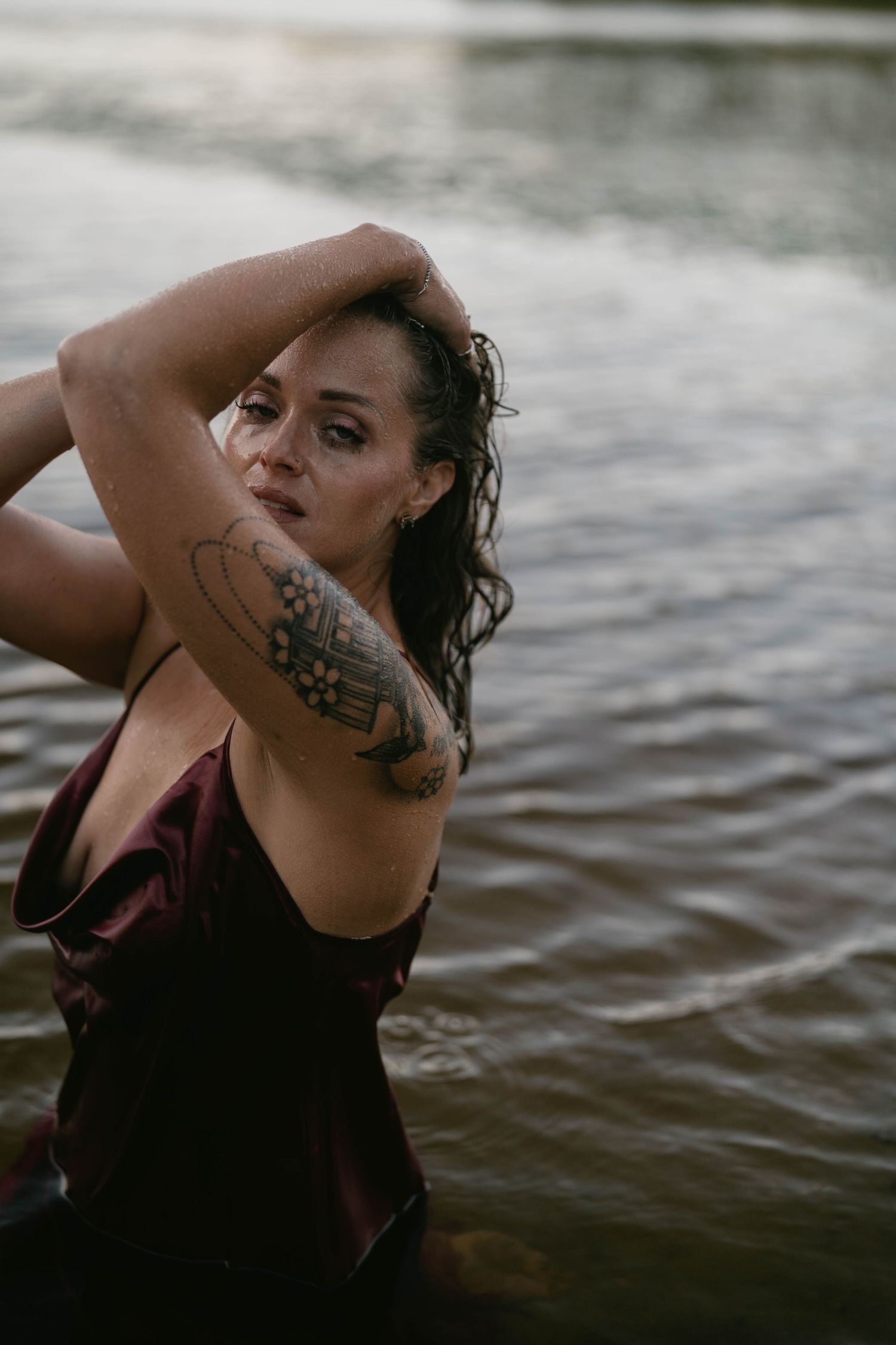Artistic water photoshoot featuring dramatic poses and tattoo art.