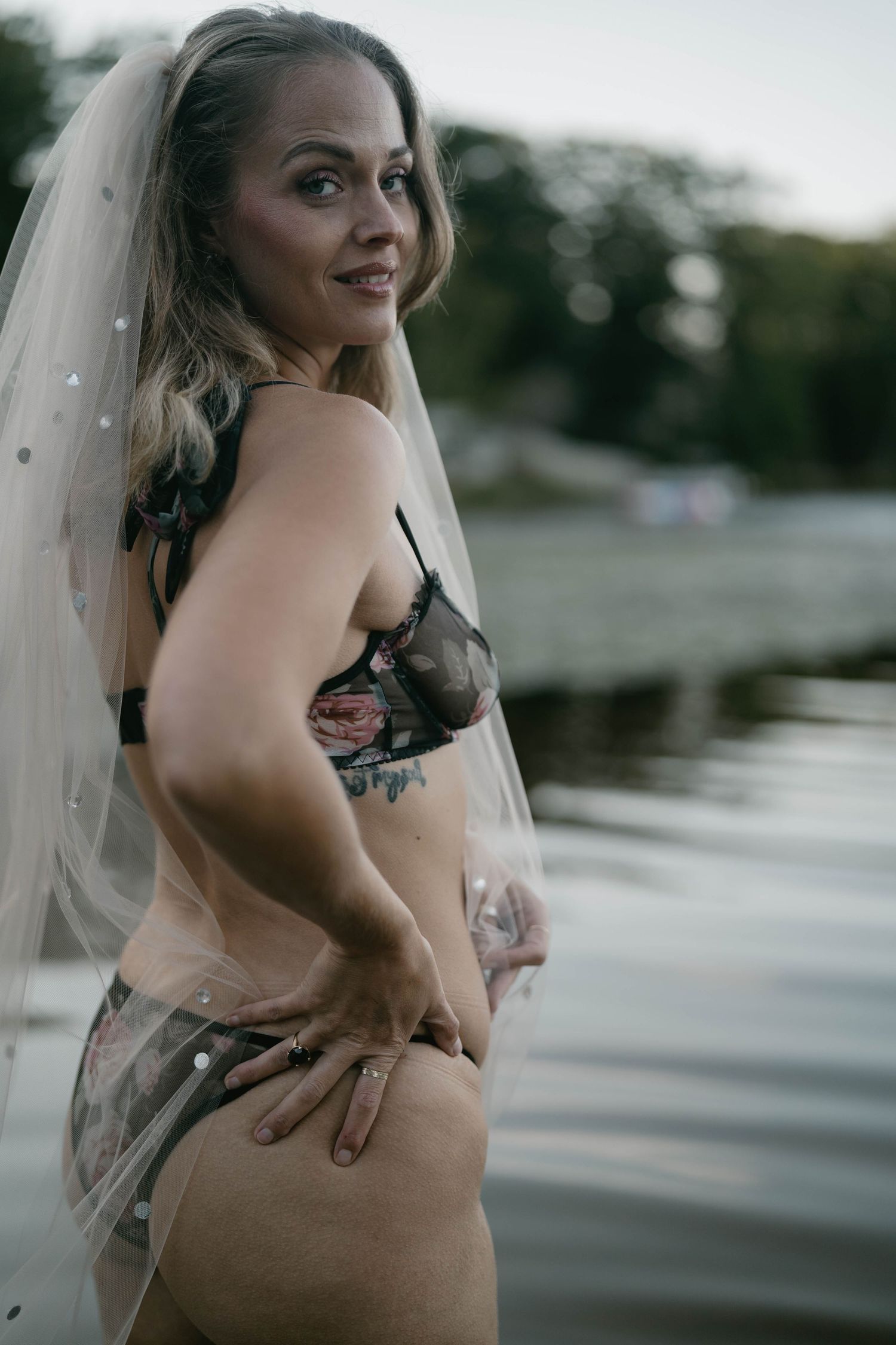 Outdoor boudoir photography featuring intricate tattoo art and veil accessories.