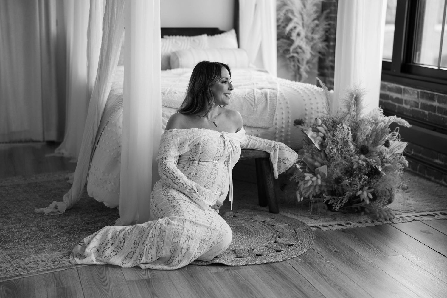 Black and white maternity photo with soft window light and lace dress.