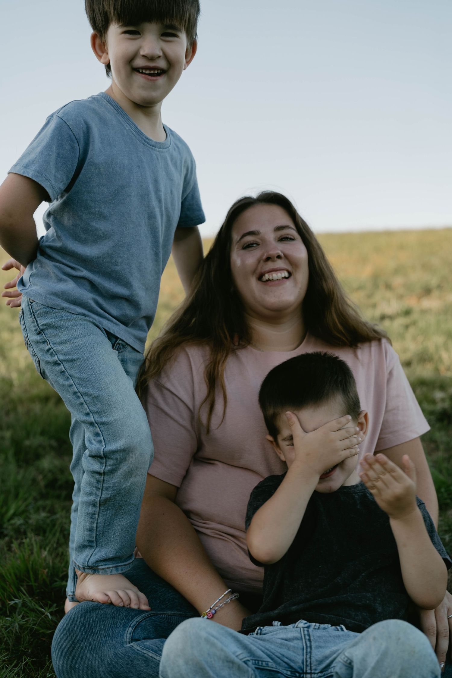 Candid family moments captured in a sunny field during sunset.