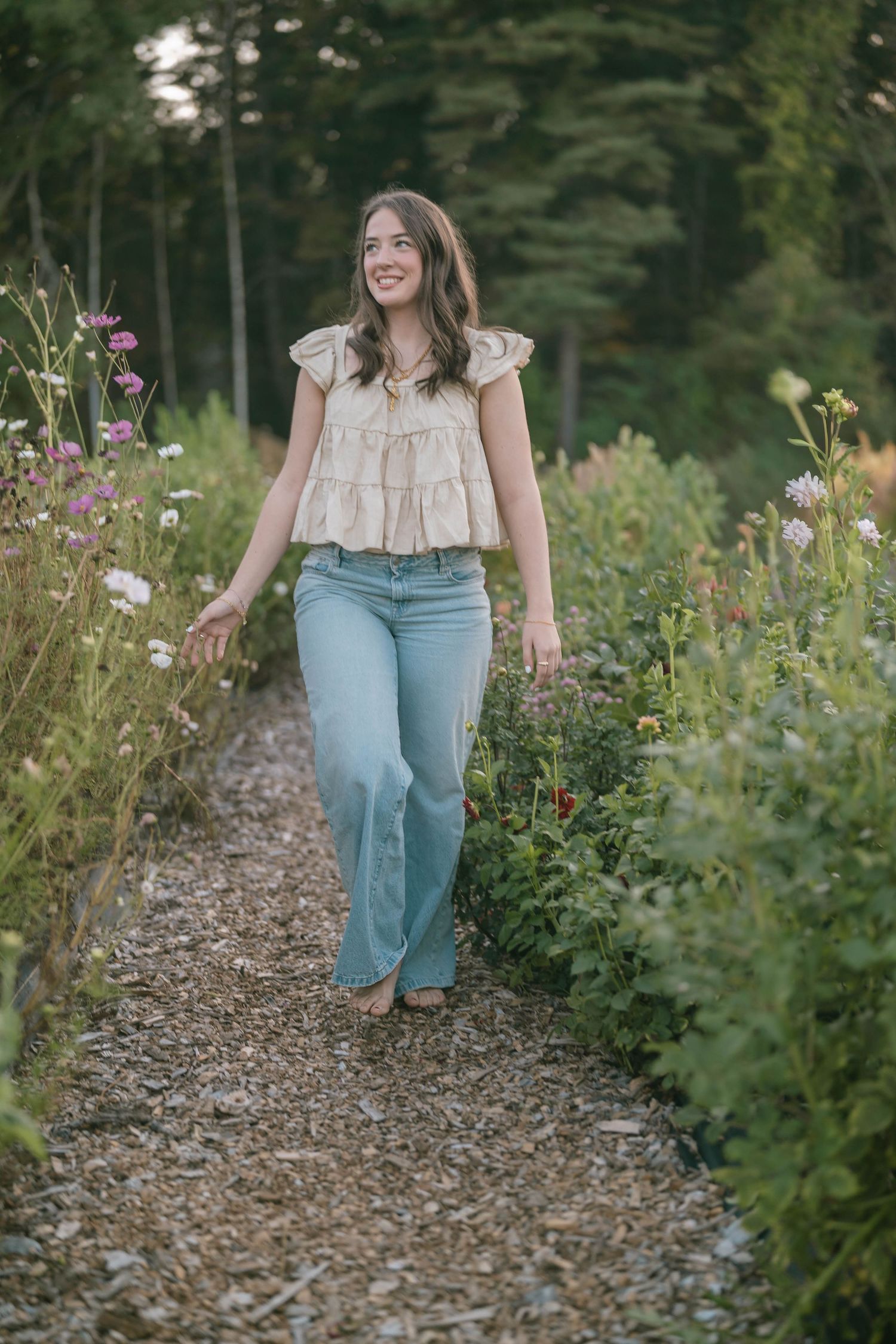 Person walking through garden path wearing light colored top and jeans.