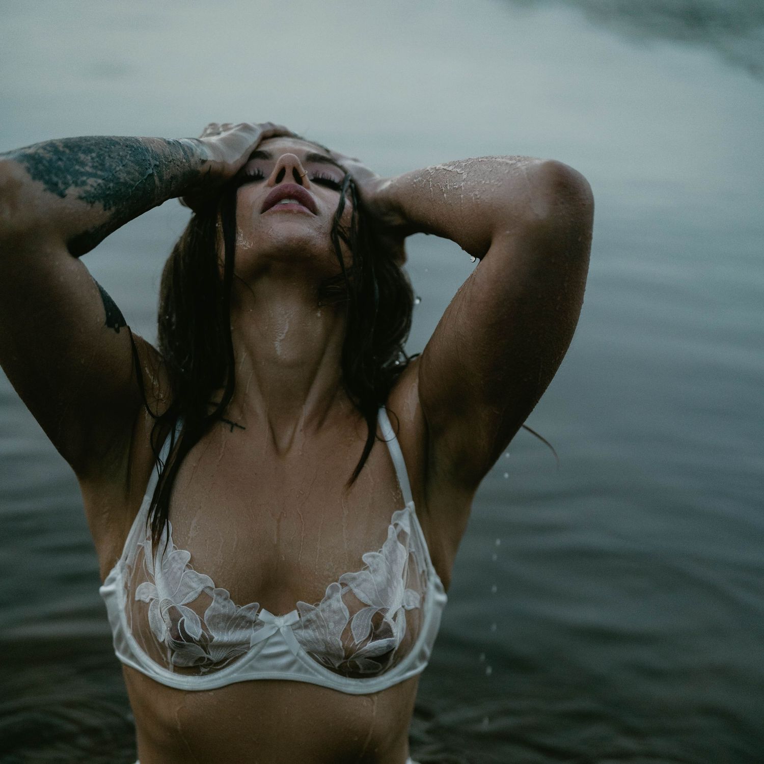 Intimate water photography session with white lace lingerie in a serene lake setting.