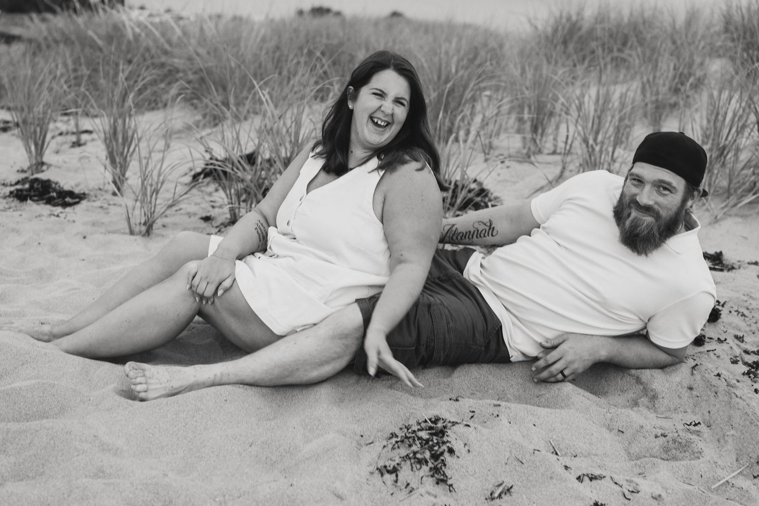 Couple embracing by the water on a sunny beach day, capturing a natural, happy moment.