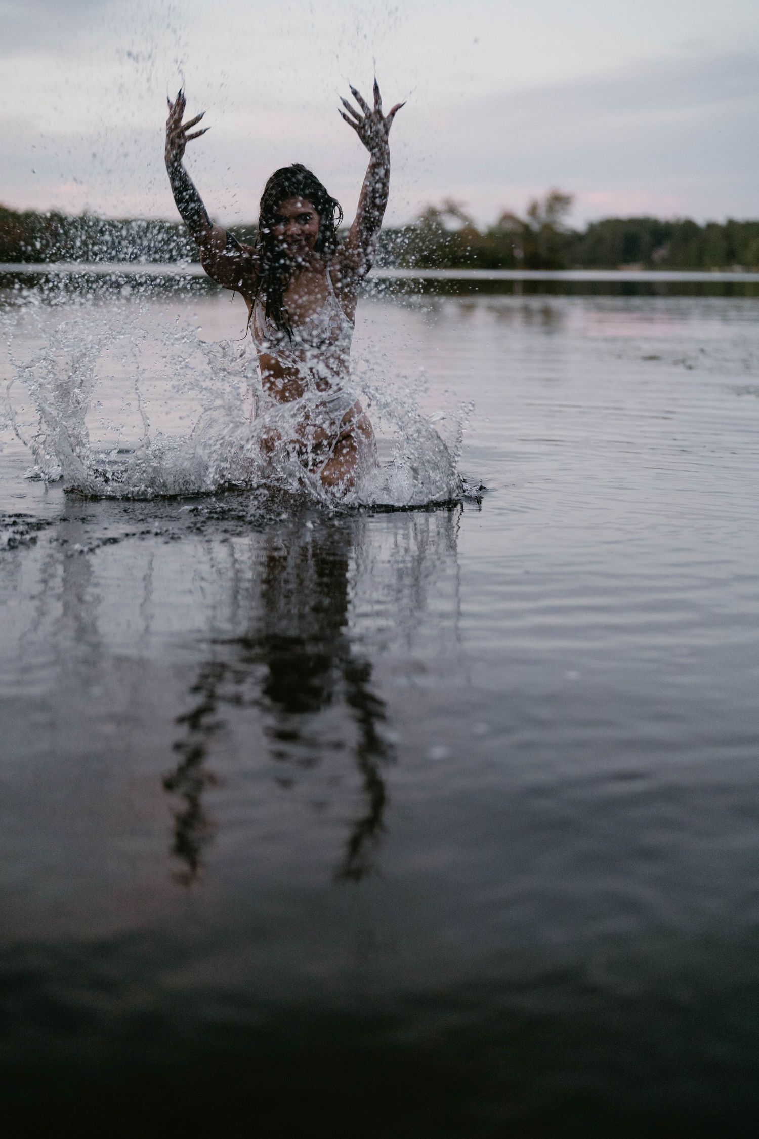 Water splashing sequence showing hands emerging from a lake surface at sunset.