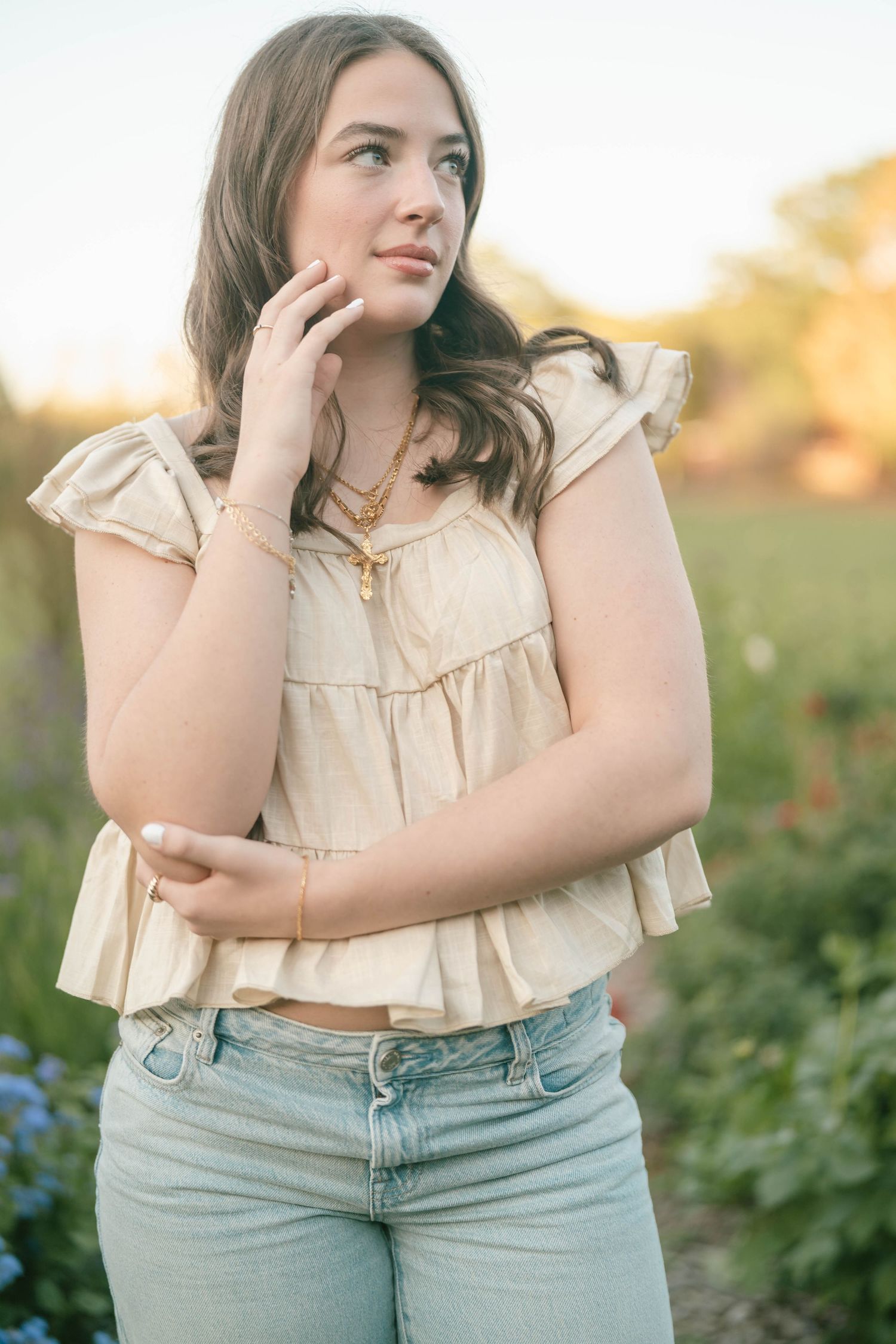 Natural light portrait in a garden wearing cream colored top and jeans.