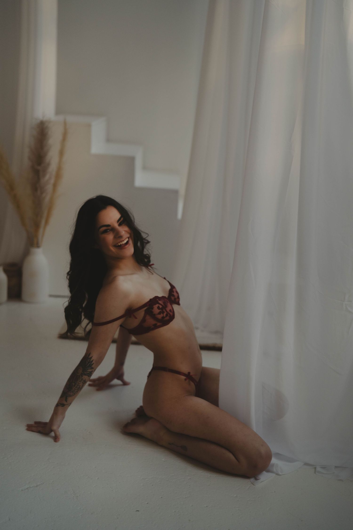 Artistic boudoir photography in a bright white room with natural lighting.