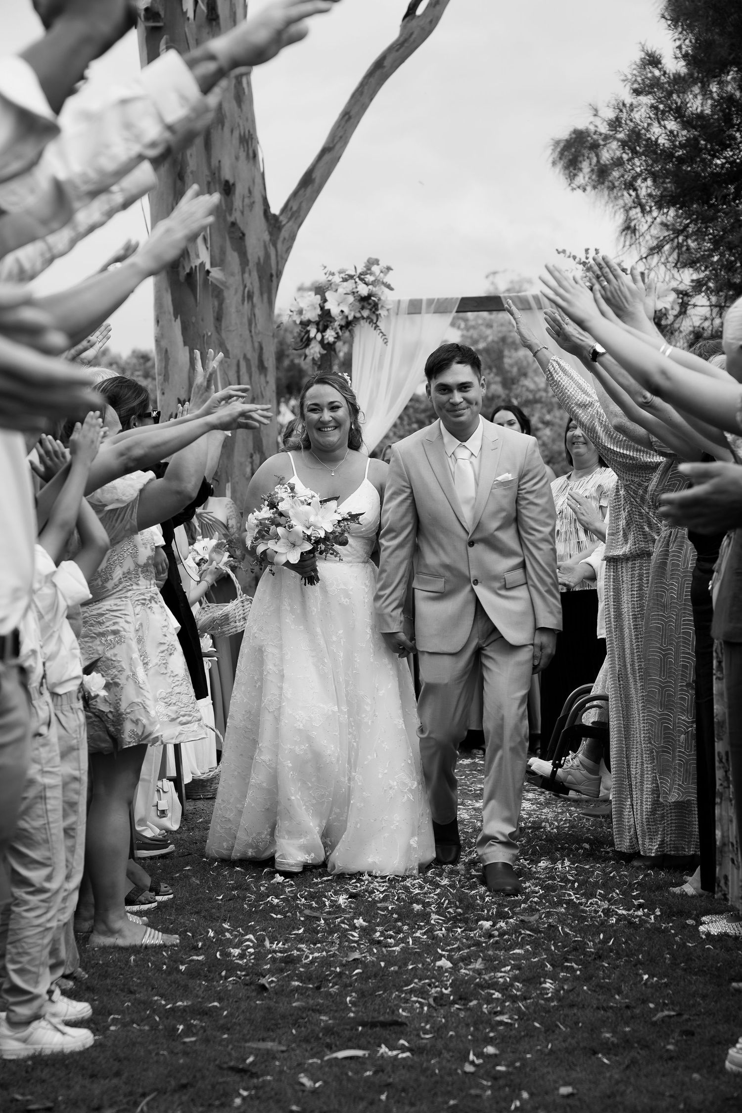 Wedding guests toss confetti as newlyweds walk through a celebratory exit line.