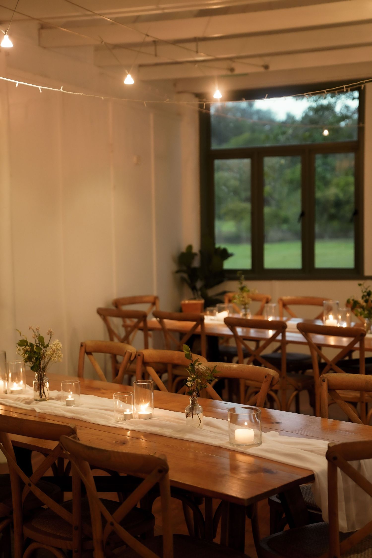 An elegant wedding reception venue with wooden tables and ambient string lighting.