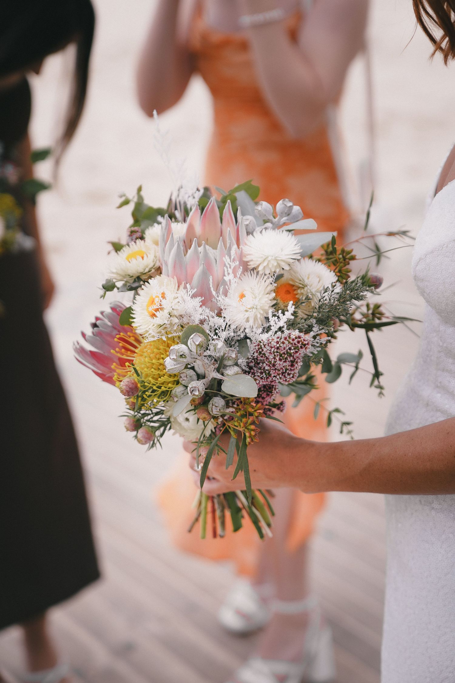 A series of bridesmaids holding small rustic wildflower bouquets with white, yellow and purple blooms.