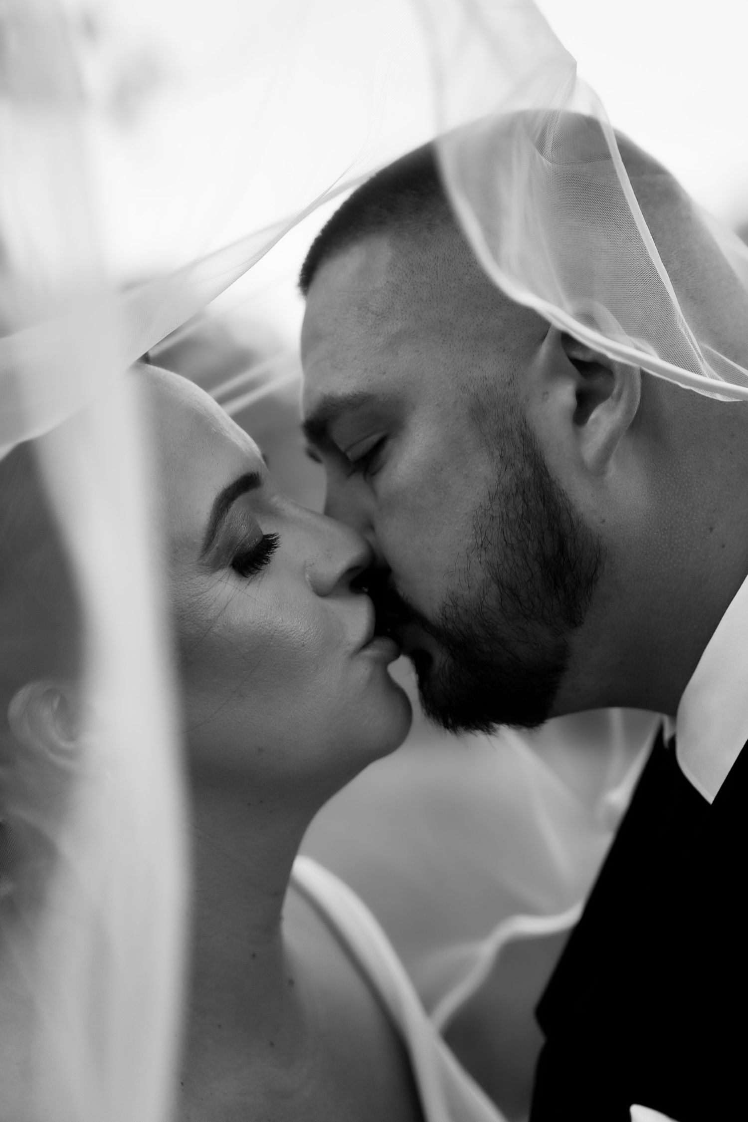 Intimate black and white close-up shots of a wedding couple sharing romantic kisses.