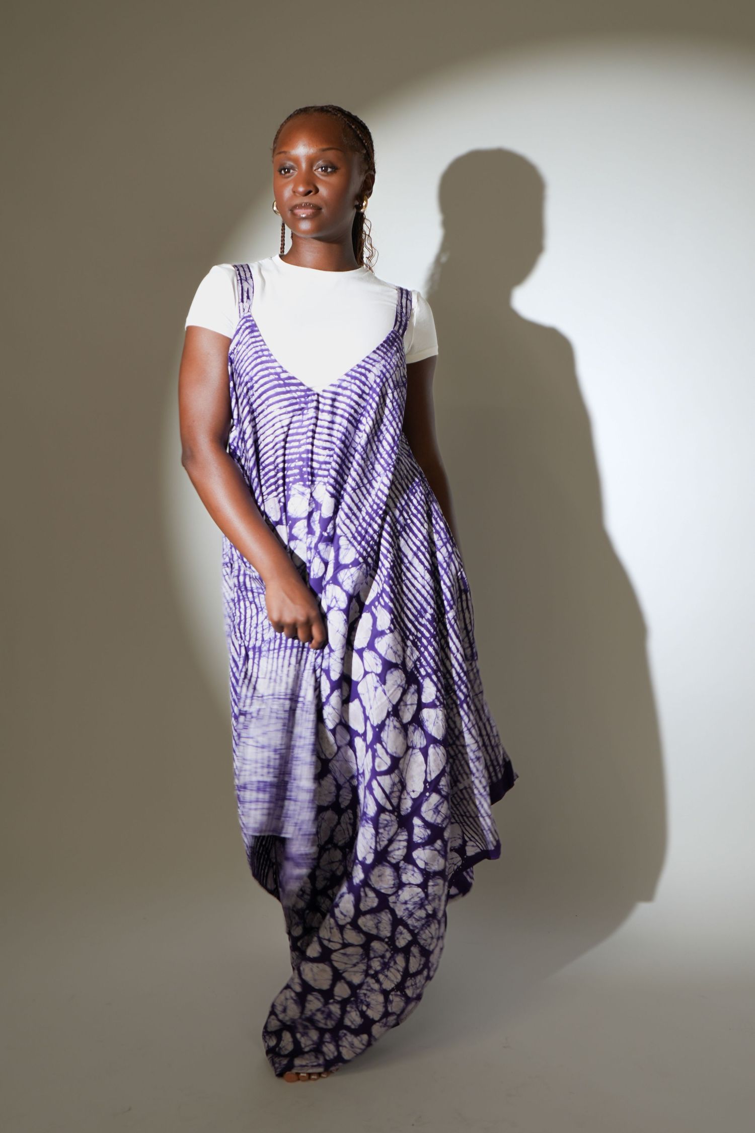 Woman wearing a white t-shirt layered under a purple tie-dye spaghetti strap maxi dress in a studio setting.
