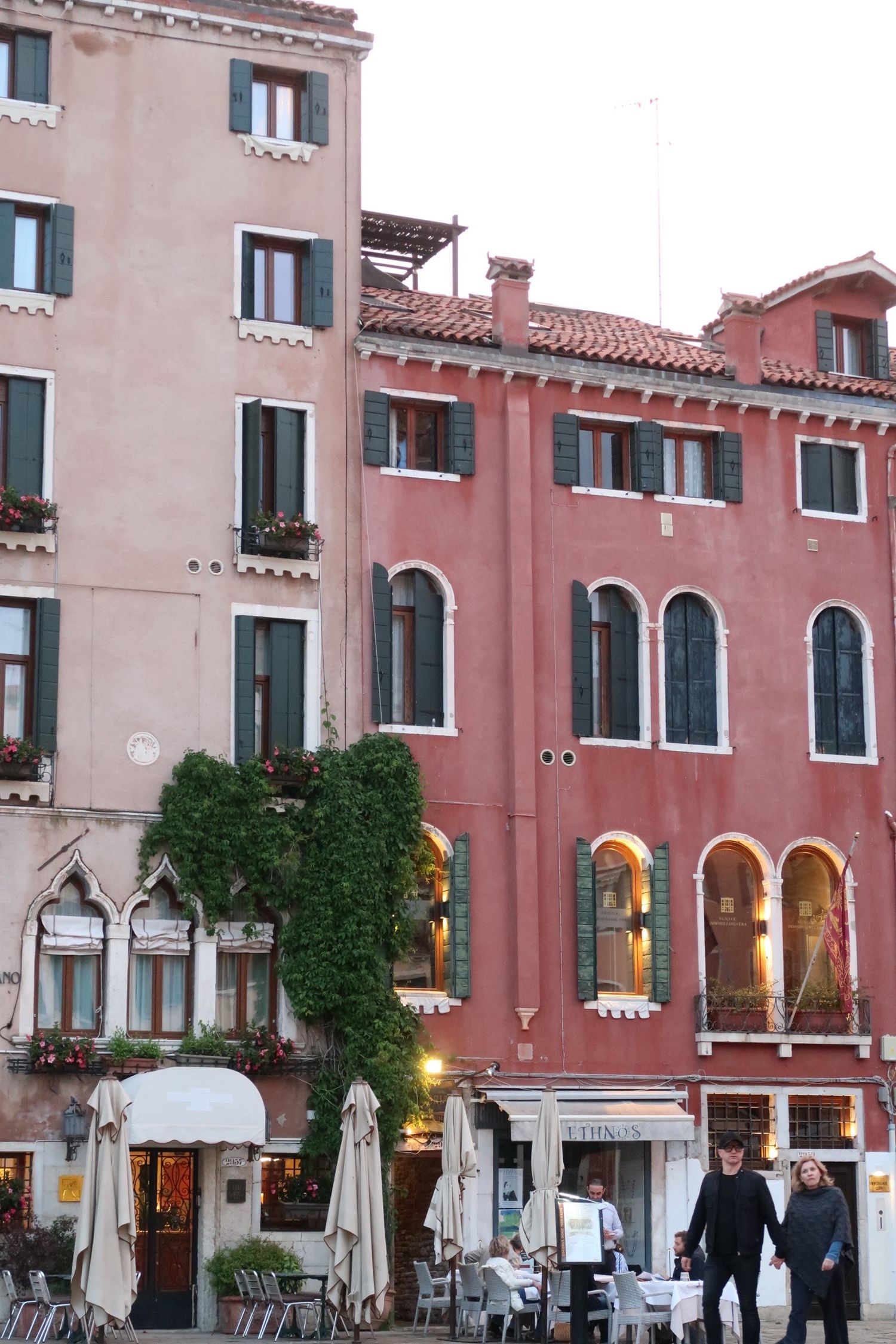 Pink and beige Venetian buildings with ornate architecture and arched windows along a street, travel photography, venice italy