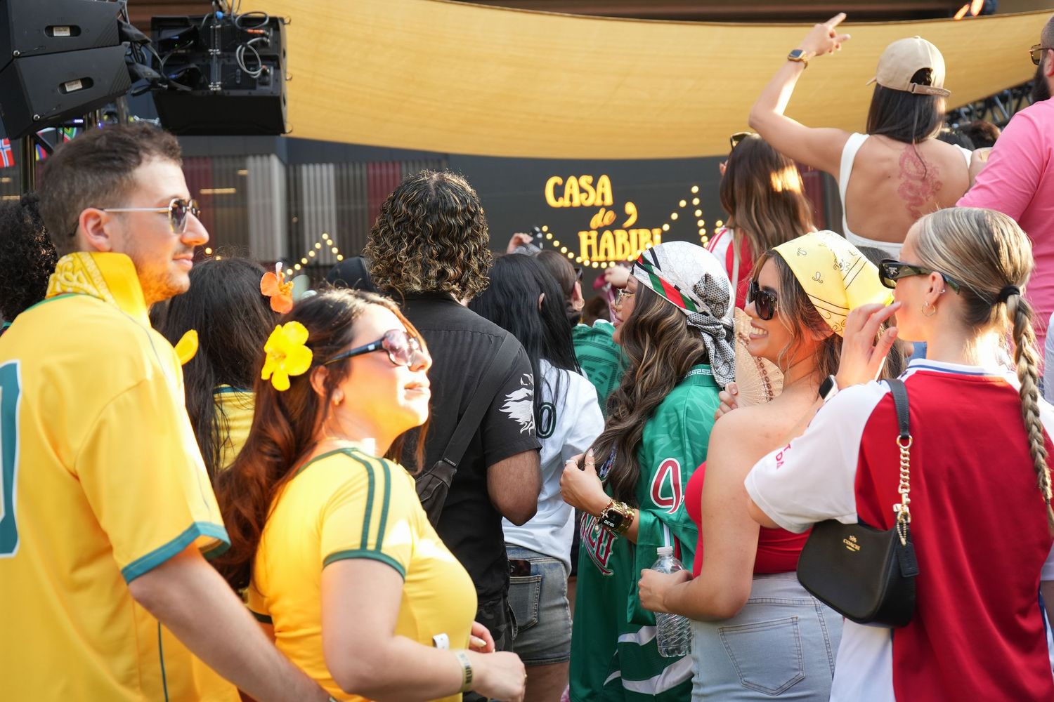 Fans in yellow and green jerseys gather outside Casa Habana during a lively soccer watch party event.