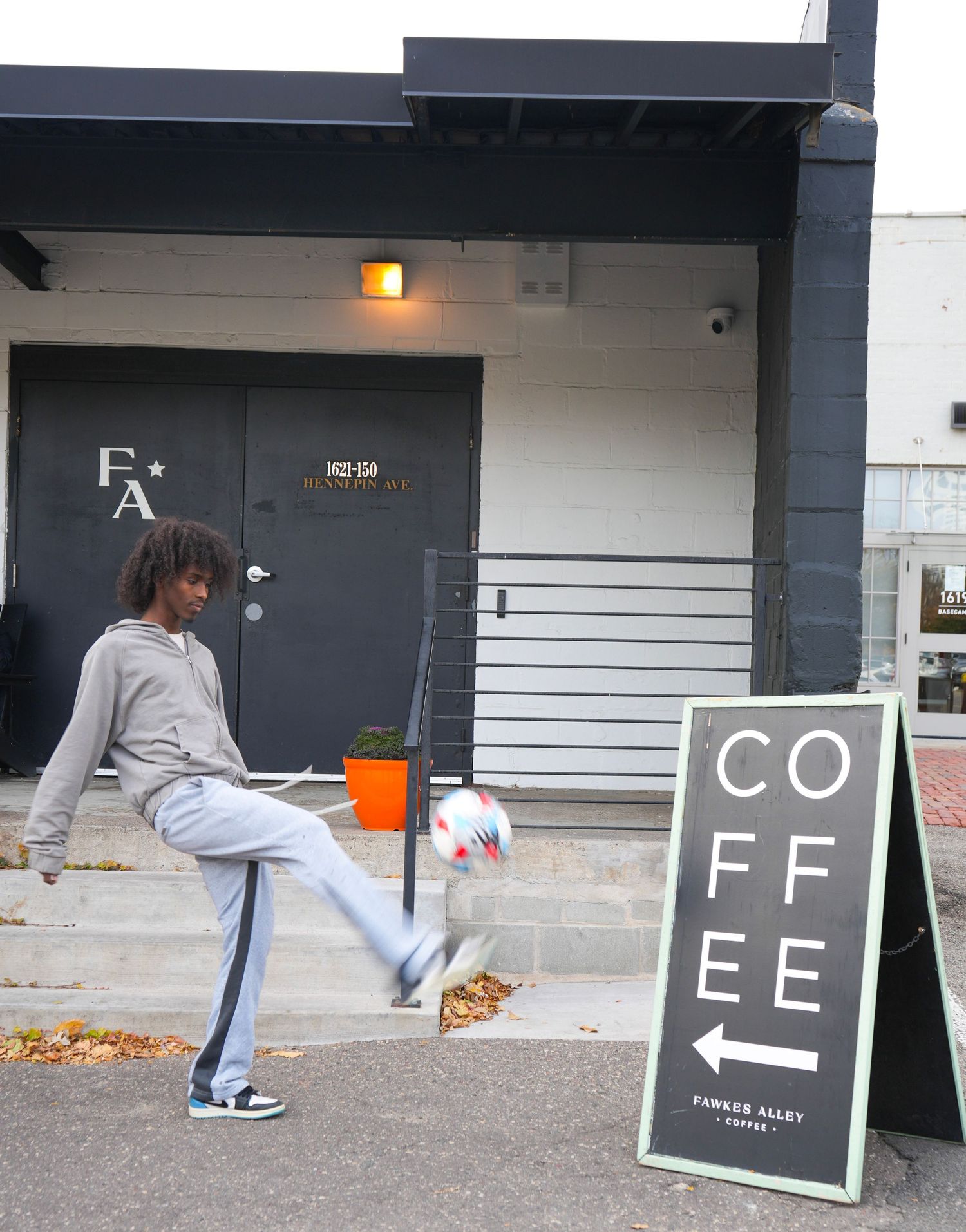 A minimalist coffee shop entrance with black accents and a sidewalk sign board, fawkes alley cafe, mn coffee shop, business photography