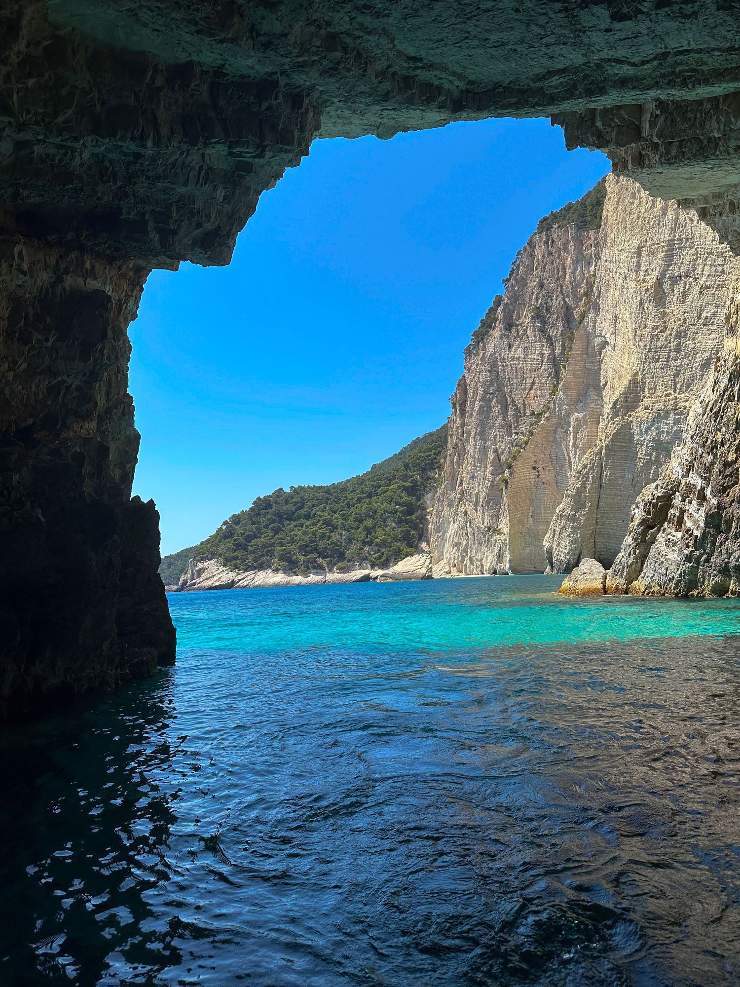 Dramatic view from inside a coastal cave showing blue waters and steep cliff walls, travel photography, zakynthos greece, greek island
