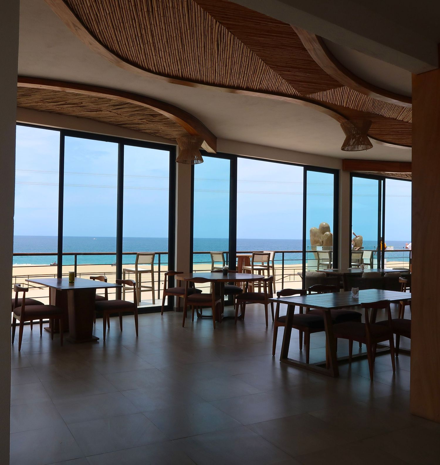 Panoramic oceanfront restaurant interior with floor-to-ceiling windows overlooking the beach, cabo, mexico, travel photography
