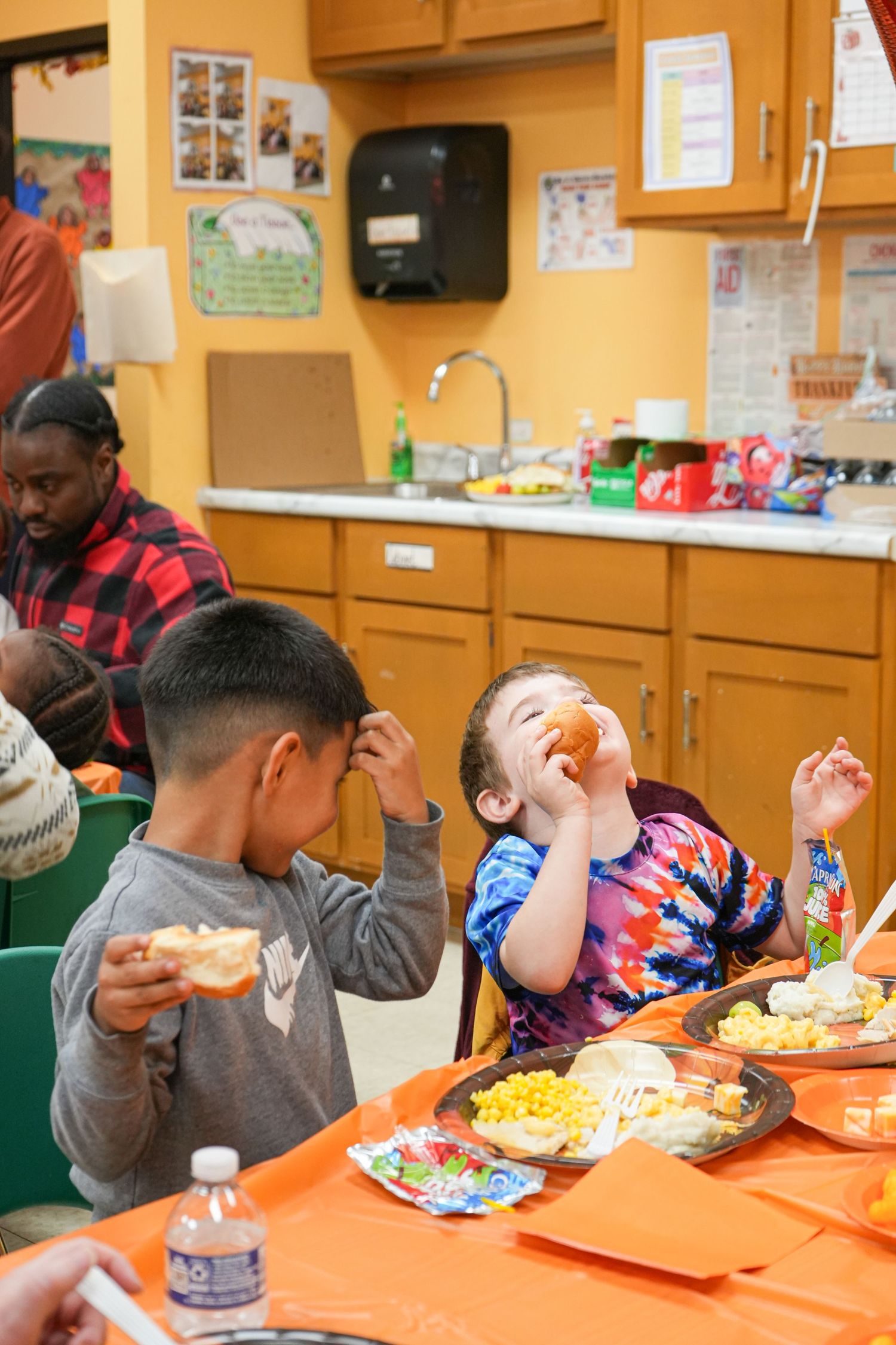 Children enjoying a meal together at orange tables in a classroom or community center, bright future star, business photography, event photo