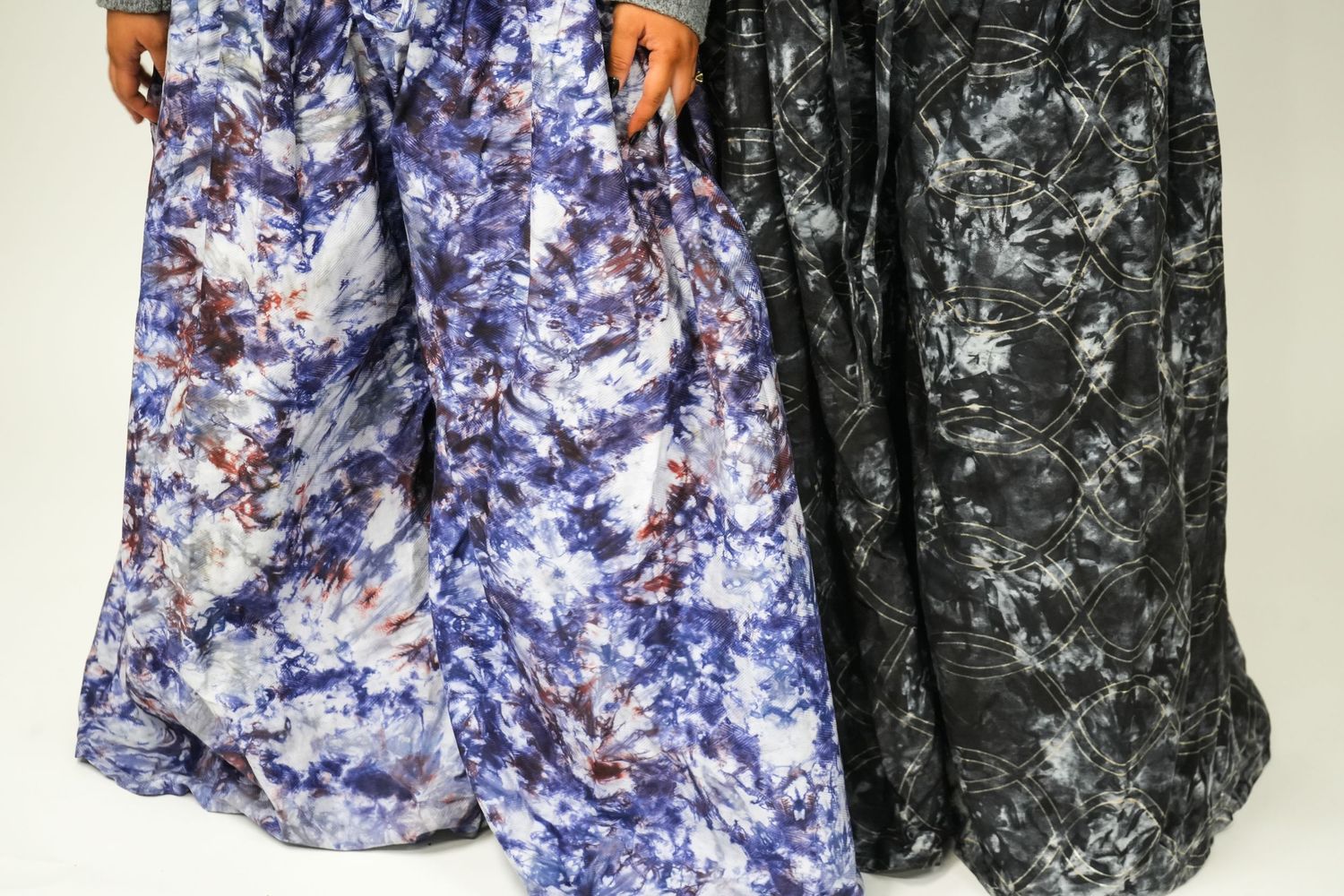 Two tie-dye patterned pants displayed, one in purple-blue tones and one in black and white, clothing brand photography, oteni designs