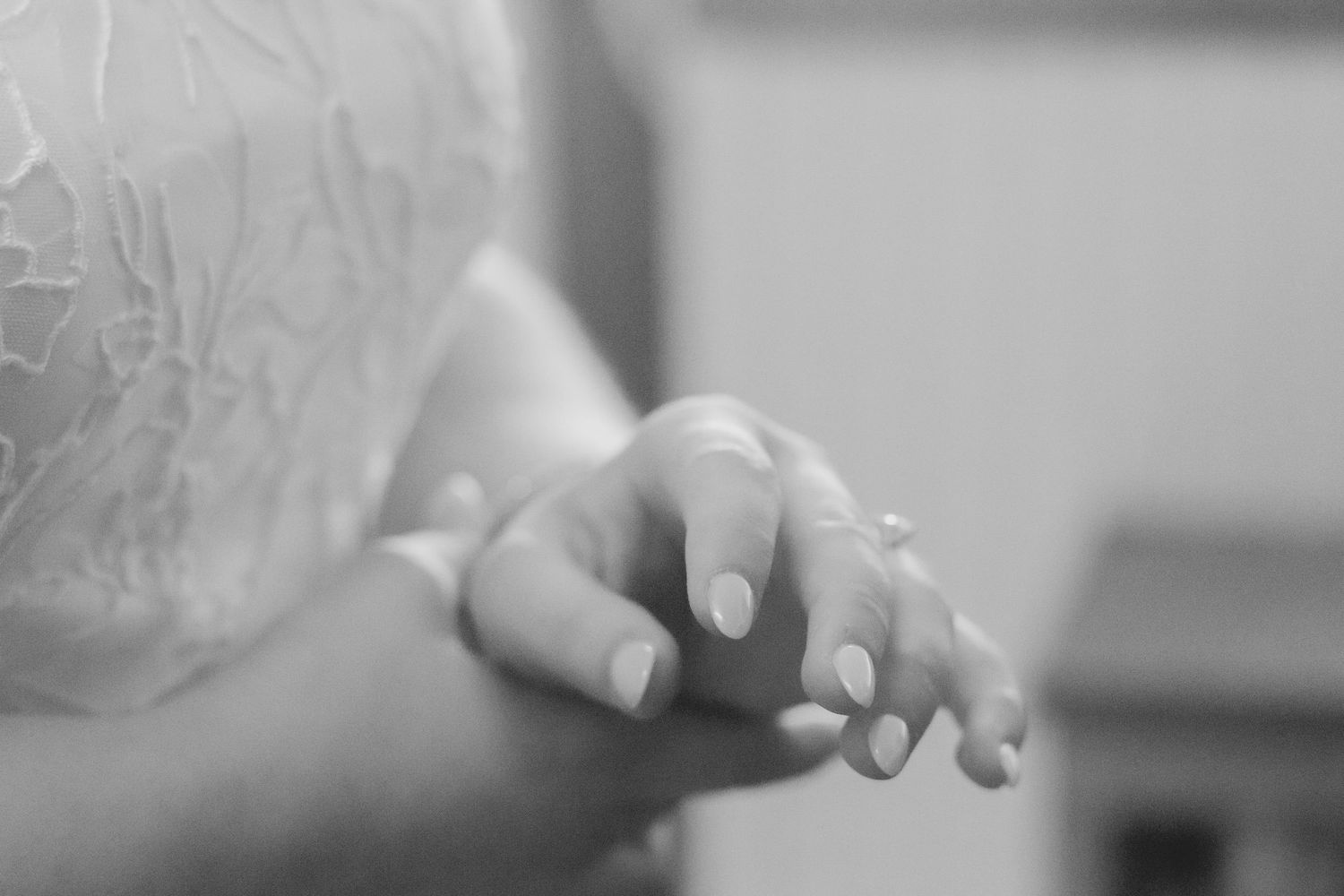 Close-up black and white detail of hands with wedding rings.