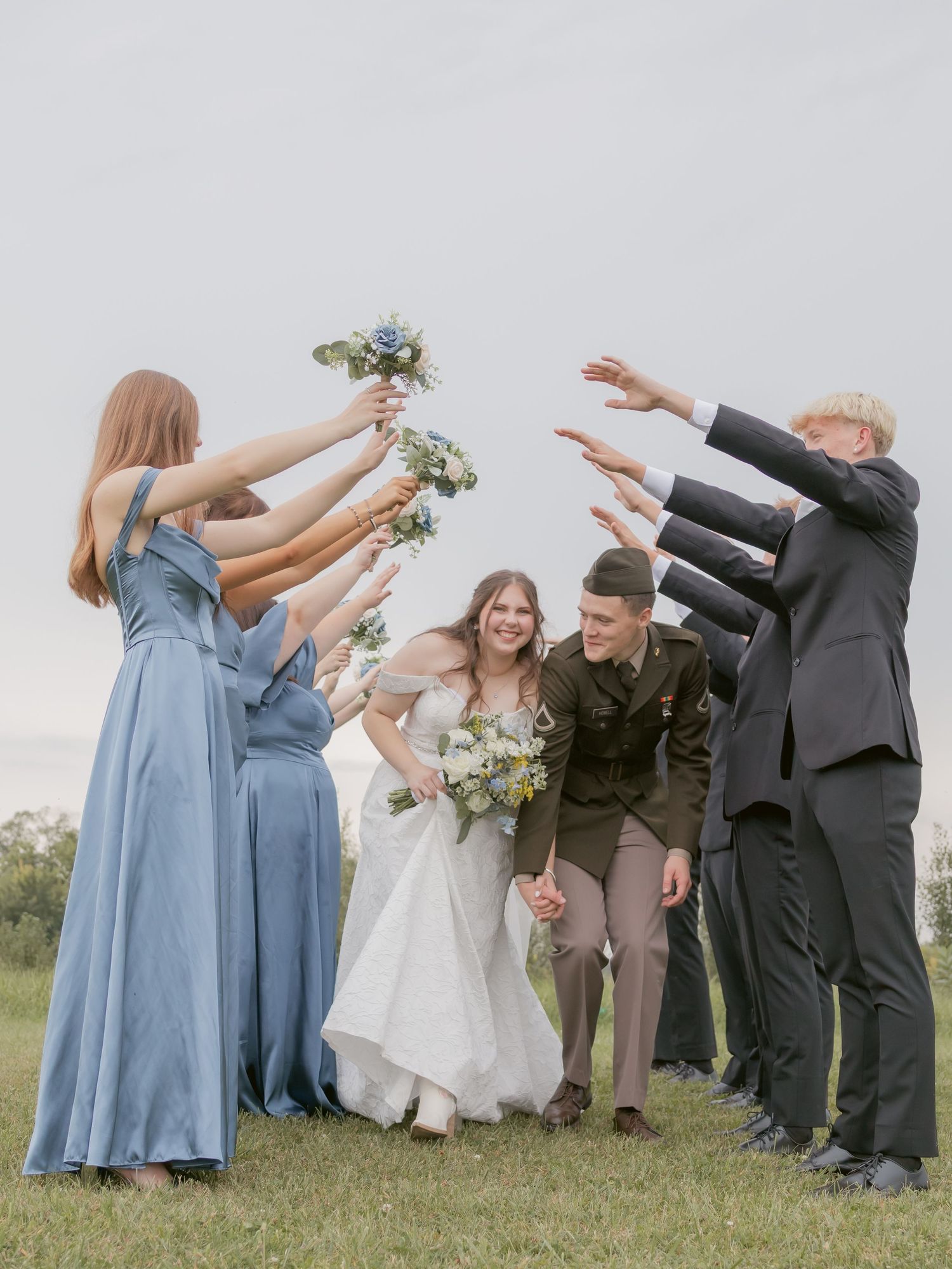 Wedding party members playfully pose with arms raised during outdoor photo session.