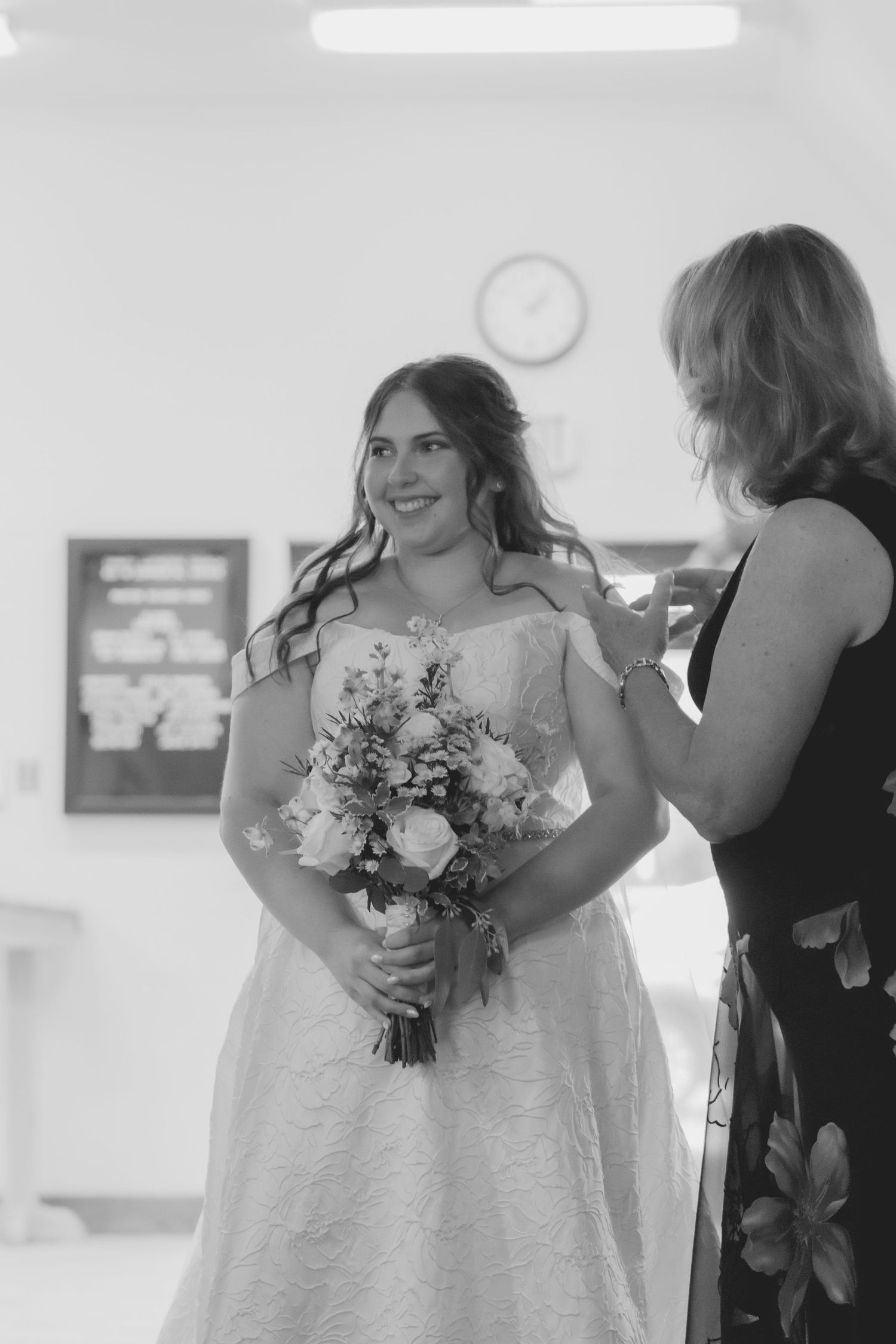 Black and white portrait of someone holding a delicate floral bouquet in a white dress.