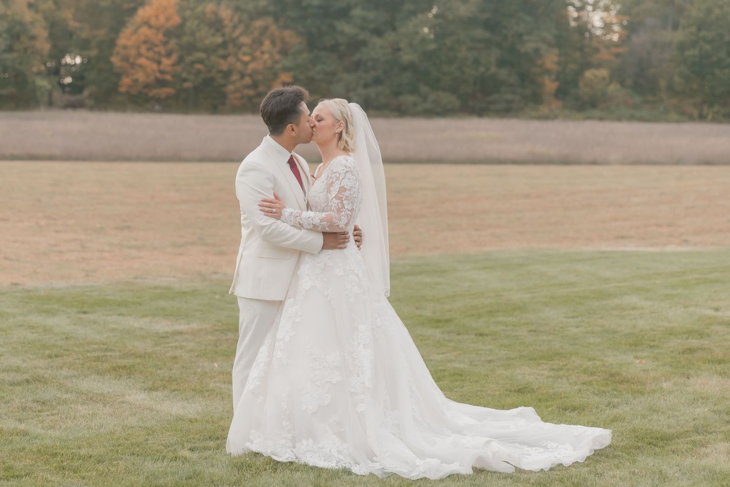 Romantic wedding portraits taken in a serene field with soft autumn lighting.