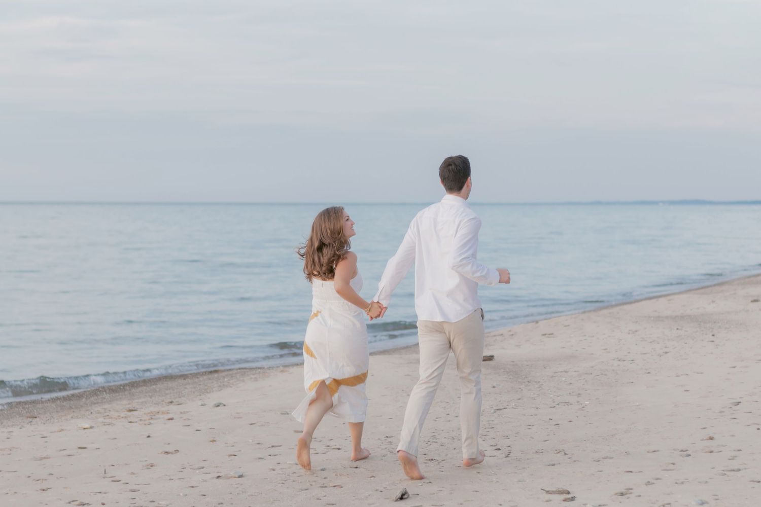 Family walking together on a white sandy beach wearing light colored clothing.