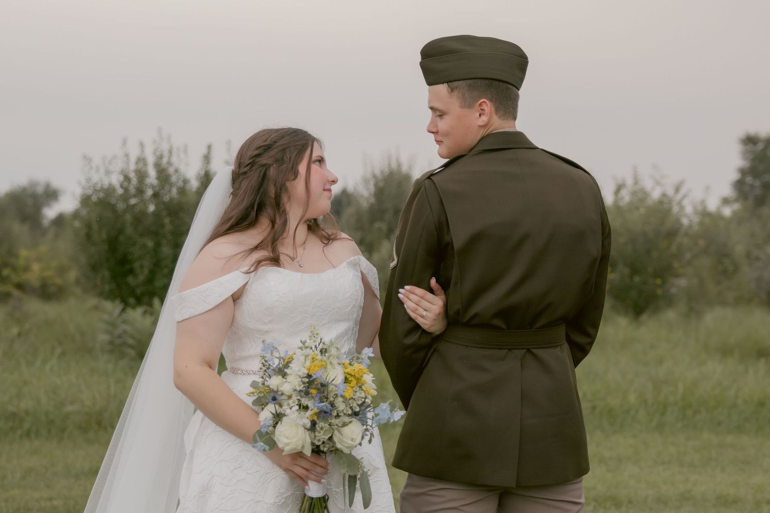 Military wedding couple poses together in outdoor garden setting.
