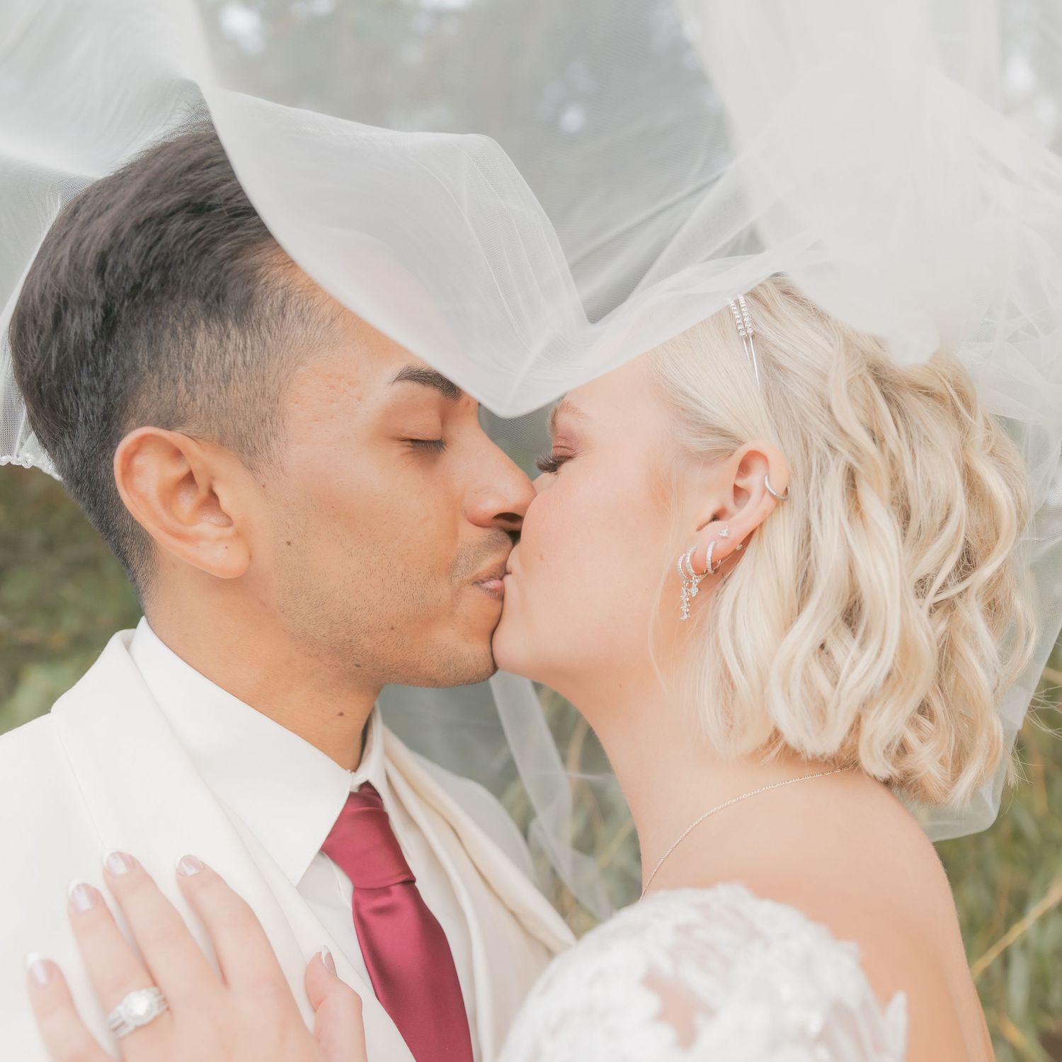 Intimate wedding moment captured under a delicate veil with soft natural lighting.