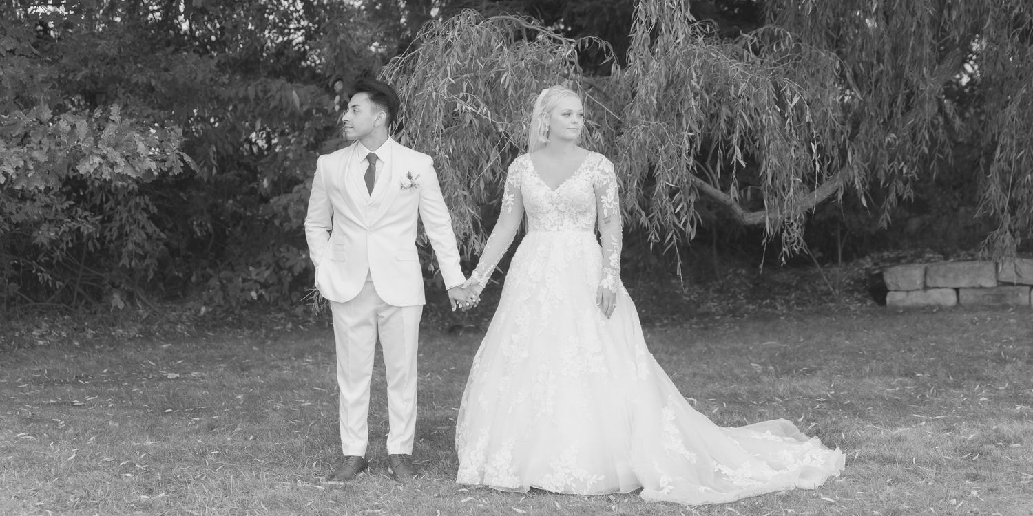 Wedding couple walks hand in hand through a scenic outdoor garden path.