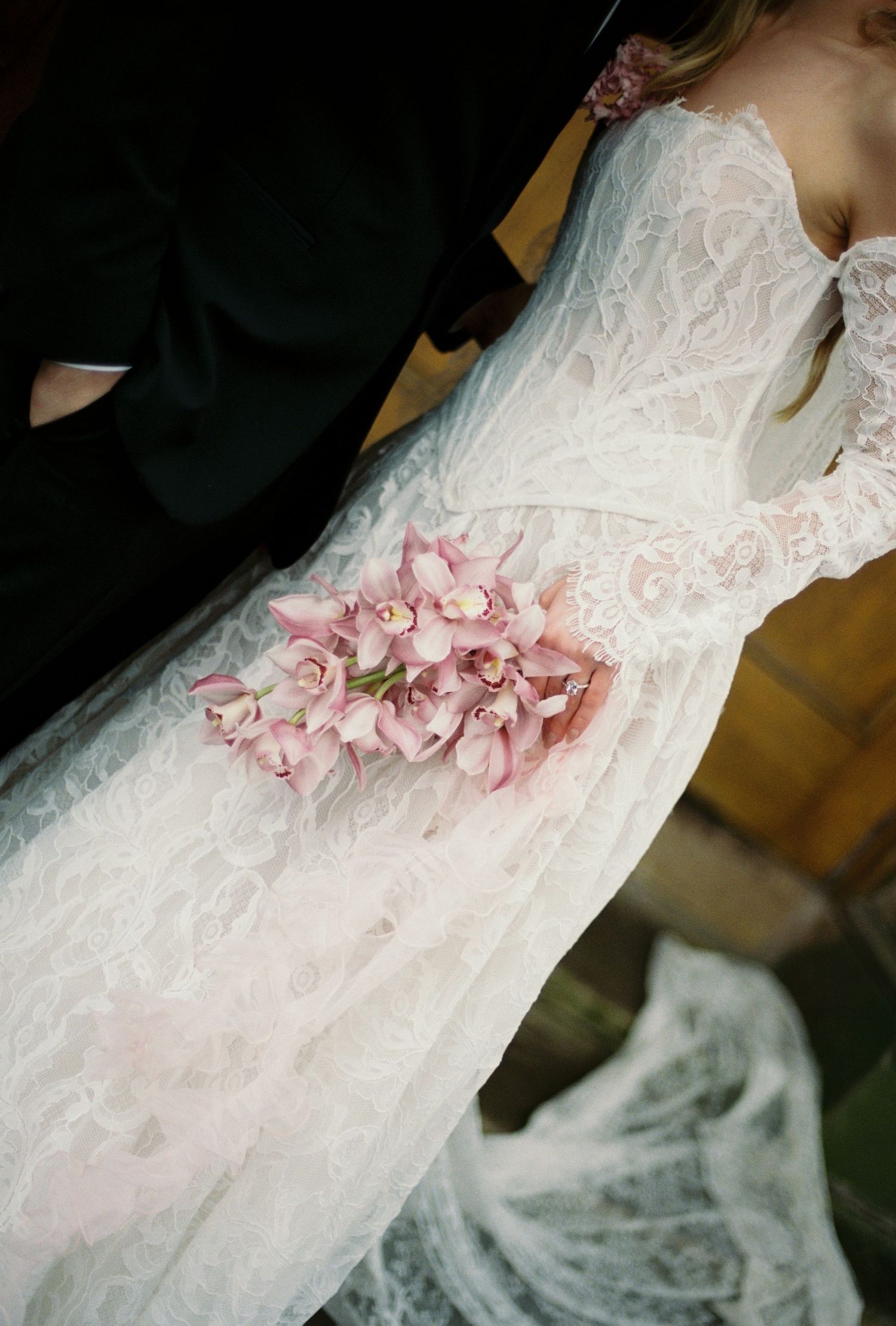 The image depicts a bride's wedding dress with a bouquet of pink flowers.
