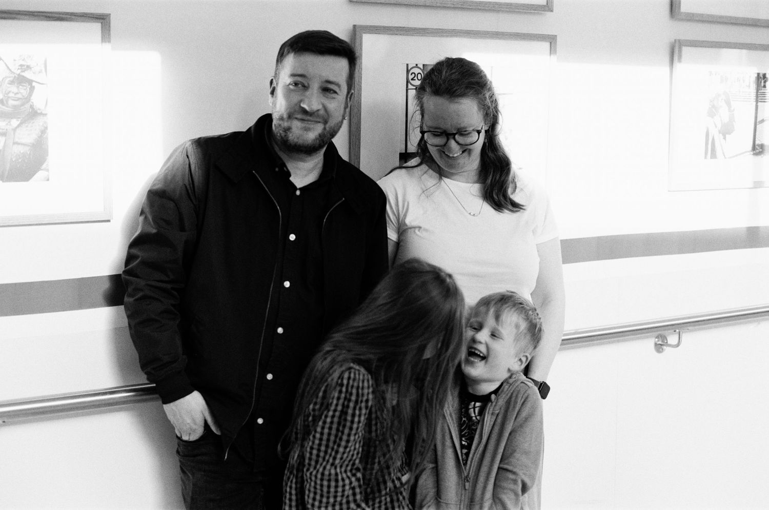 Black and white photo of a smiling family with two adults and two children posing together indoors.