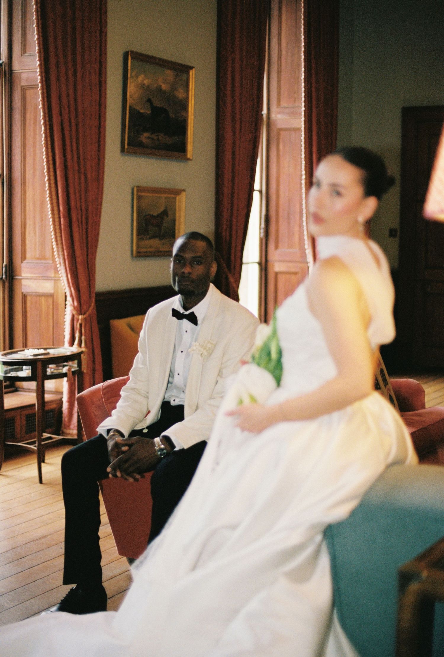 The image shows a bride in a white wedding dress posing in a formal setting.