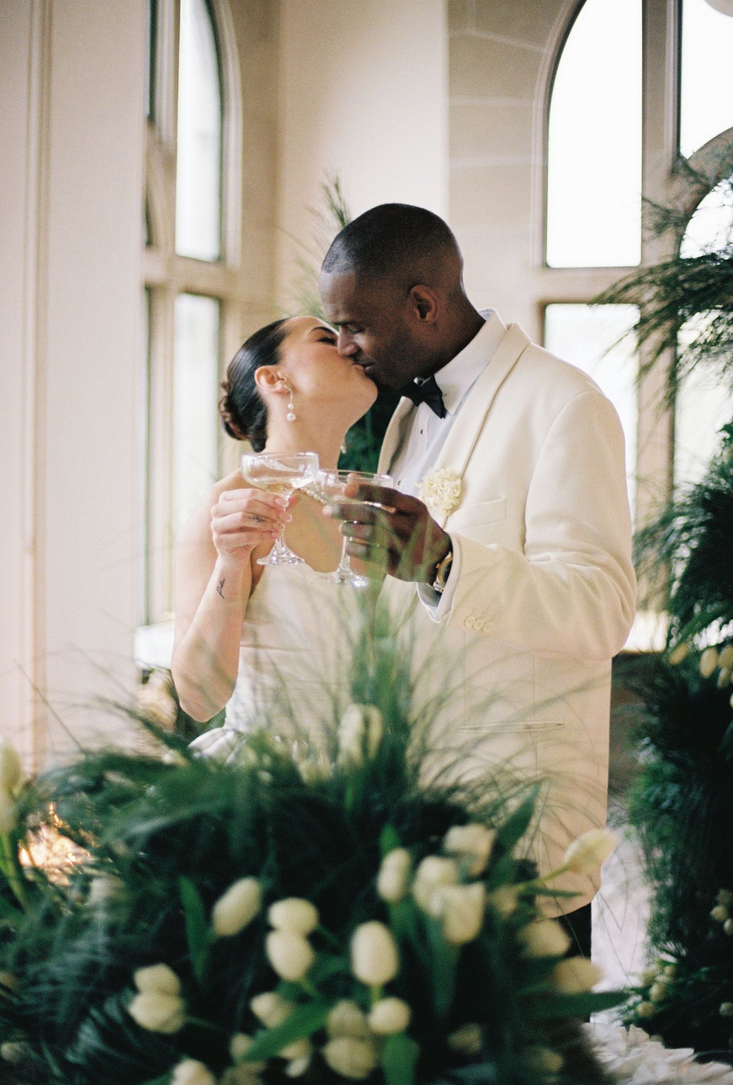 A couple dressed in formal attire embraces in a wedding venue.
