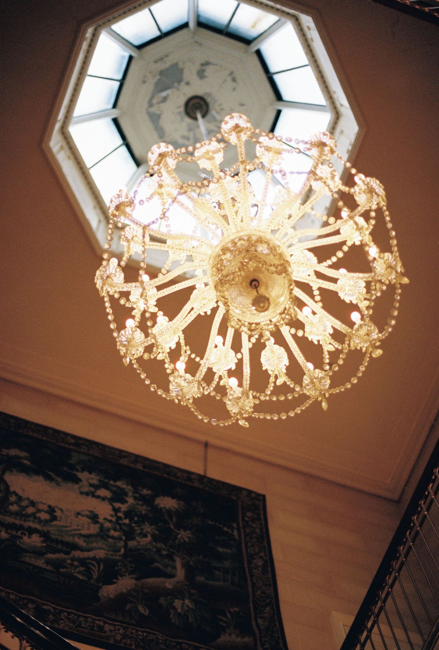 A close-up of a crystal chandelier hanging from the ceiling of a wedding venue.