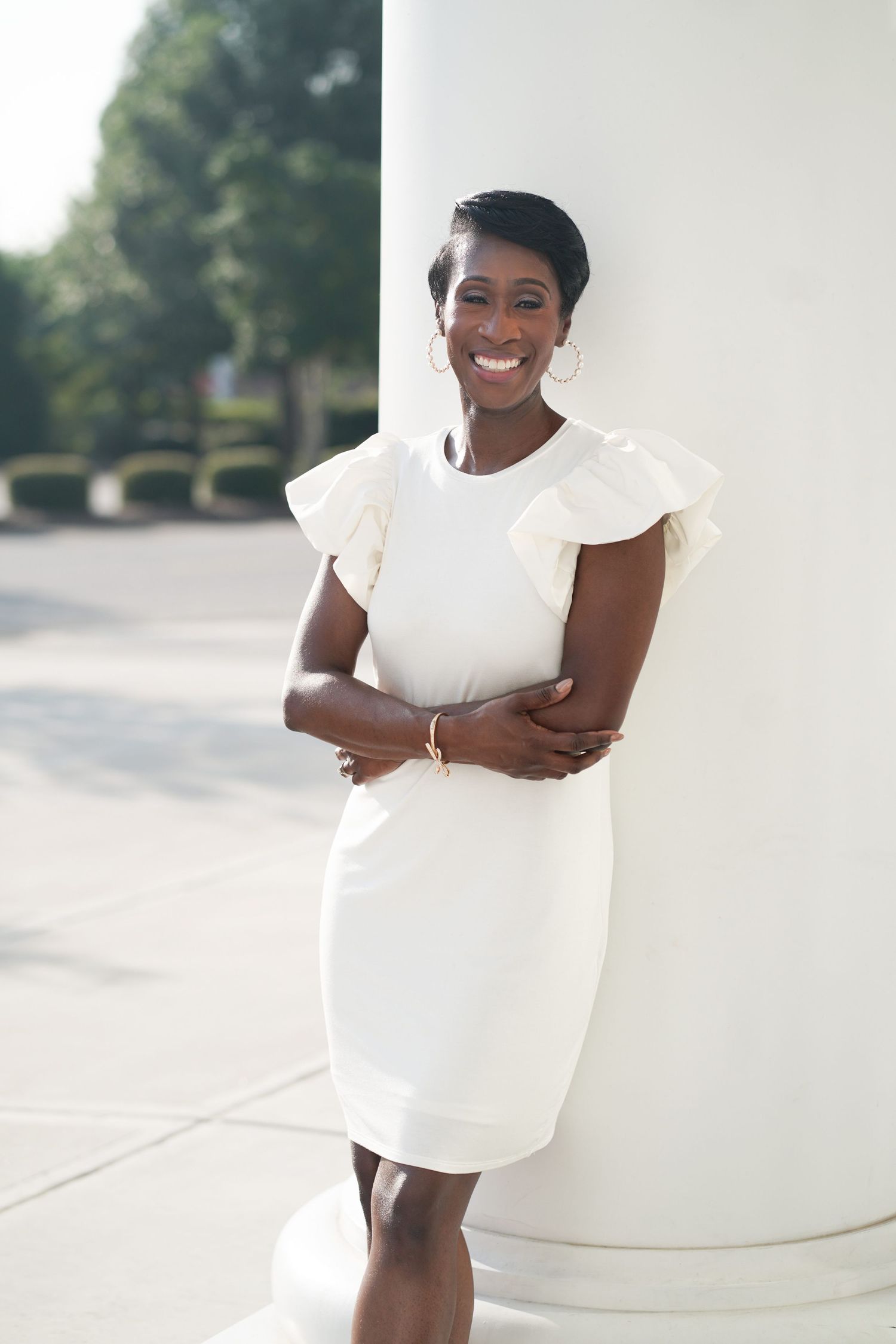Person in a white dress smiling and posing against a light background.