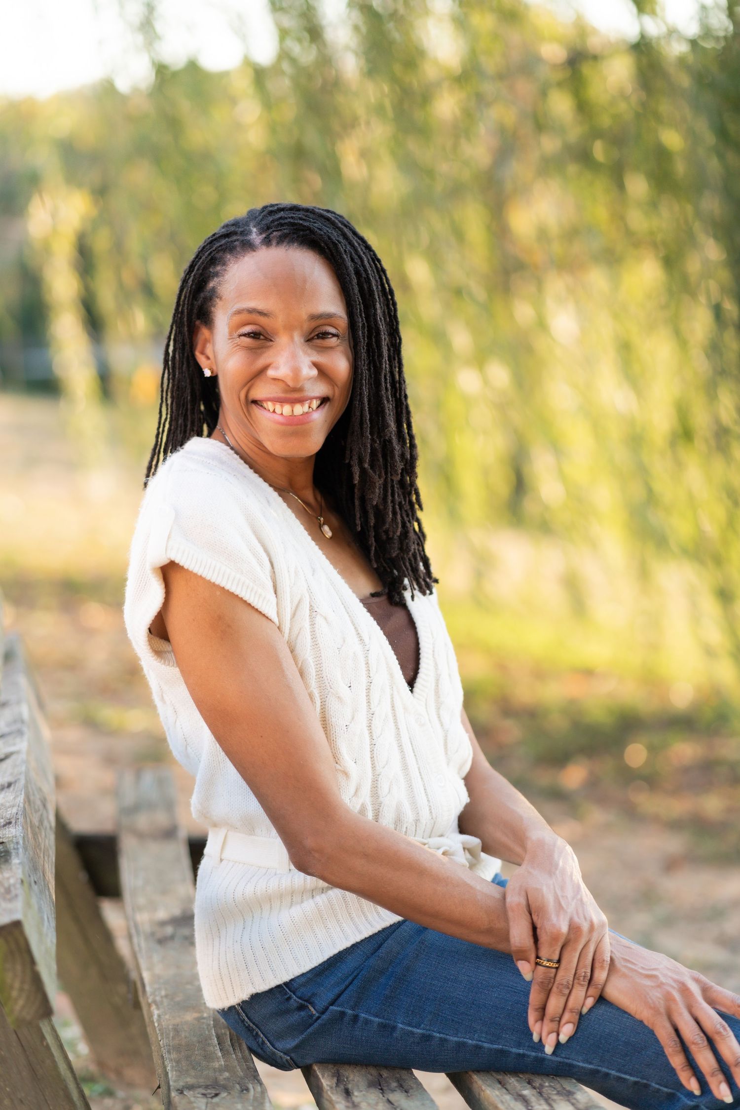 Casual outdoor portraits on wooden fence wearing white sweater and jeans.