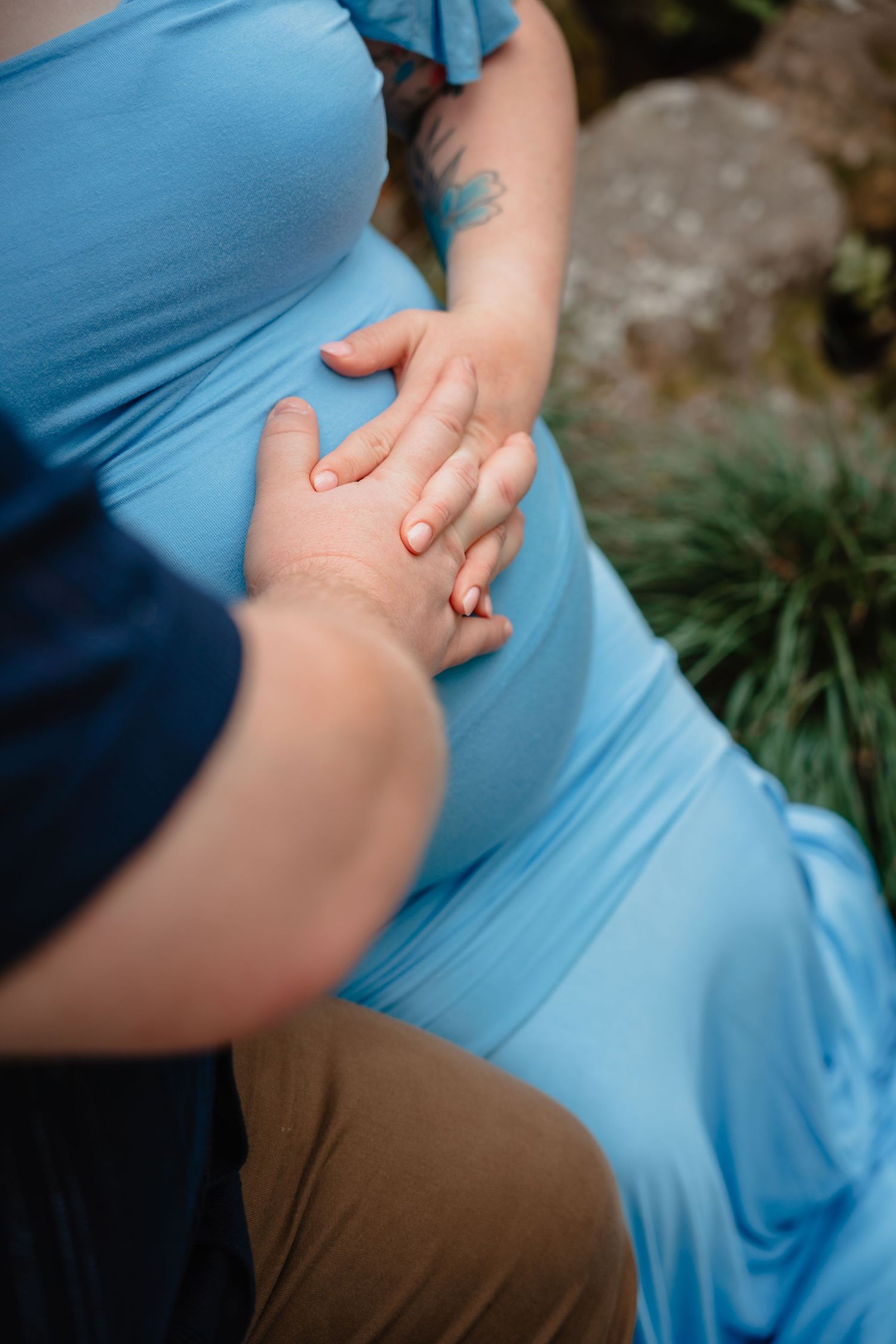 A close-up view of a pregnant woman's belly, with her hands resting on it.