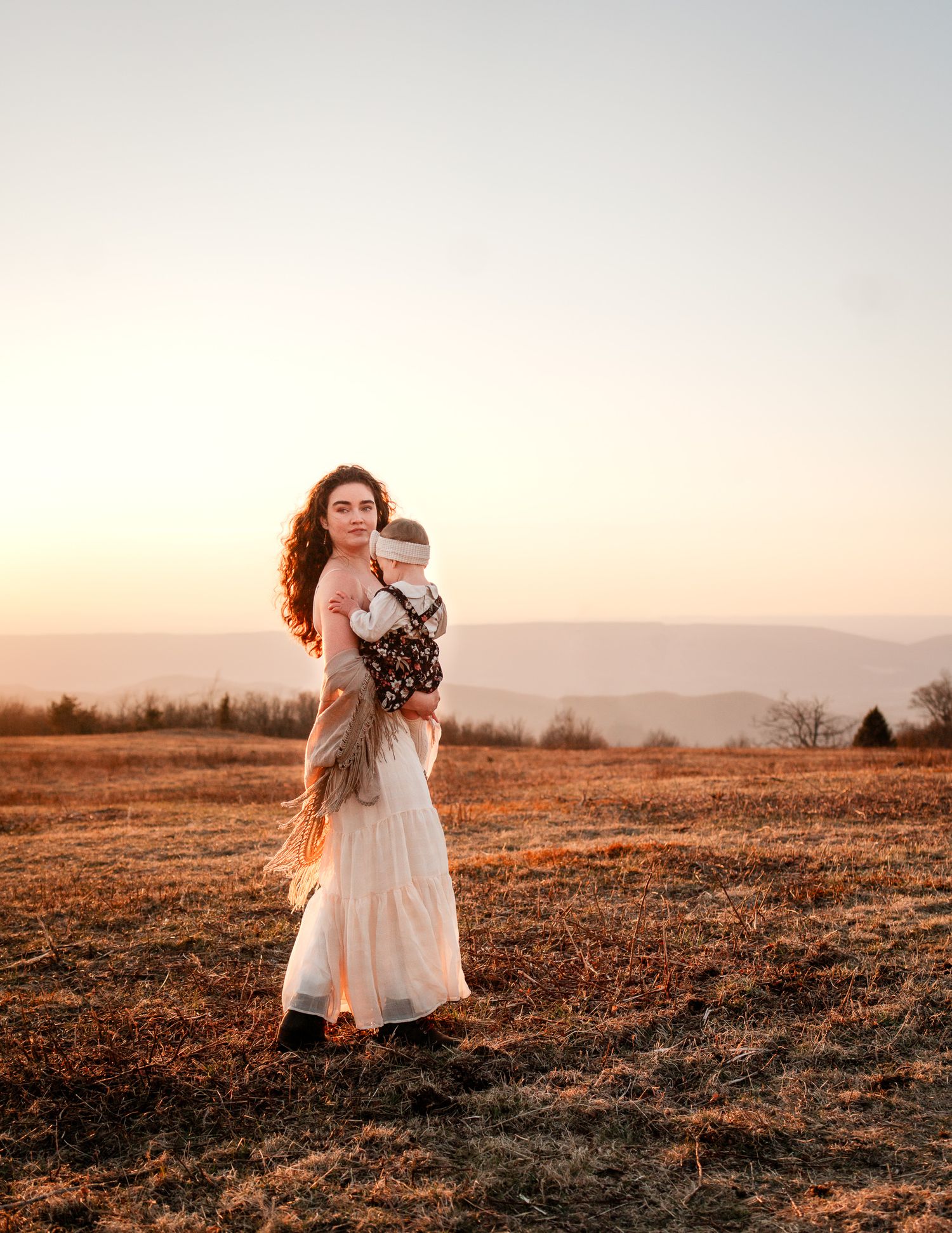 A tender moment captured in a field during golden hour sunset.