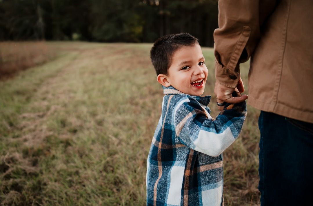 A playful moment captured in a field with someone wearing a blue plaid shirt.