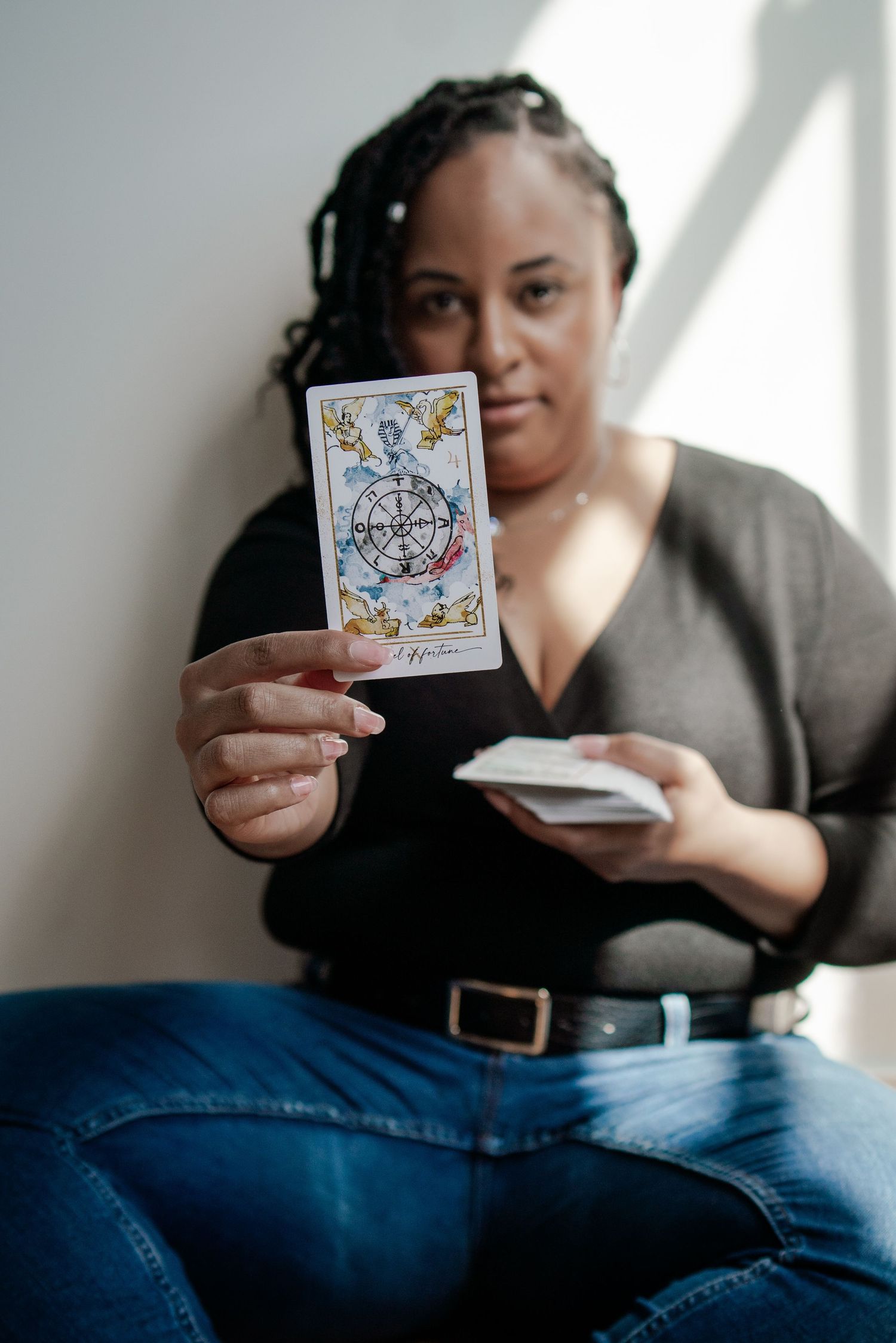 Person holding playing cards while sitting on a couch in casual attire.