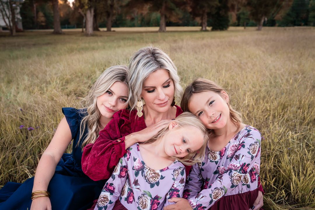 A group poses together in a field during sunset wearing coordinated burgundy and floral outfits.
