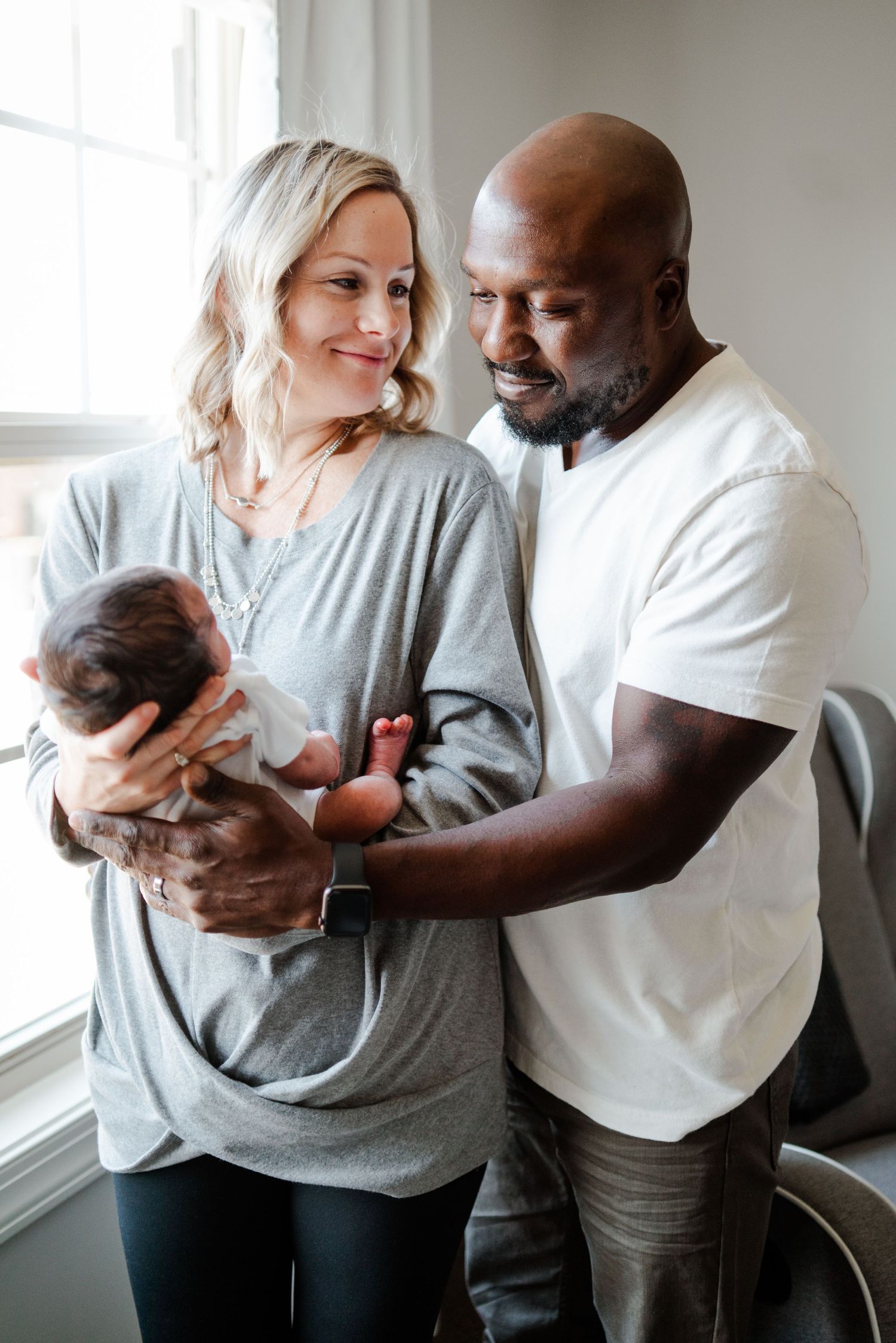 Happy couple sharing tender moment while holding their newborn baby.