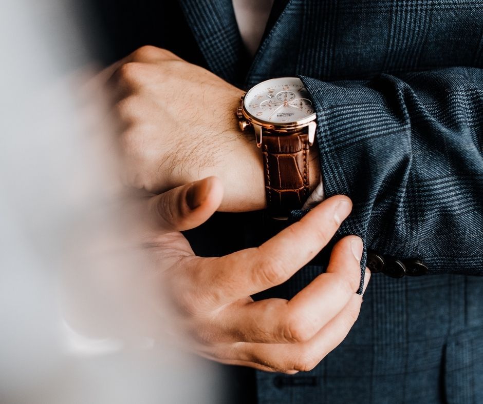 Close-up shots of hands adjusting a brown leather watch strap and timepiece against a dark textured background.