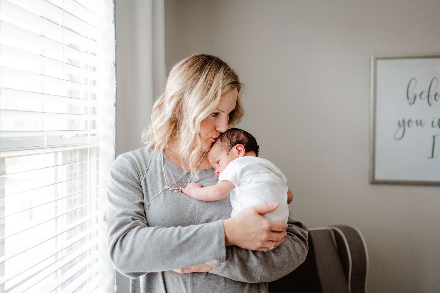 Gentle moments between parent and newborn by sunlit window.