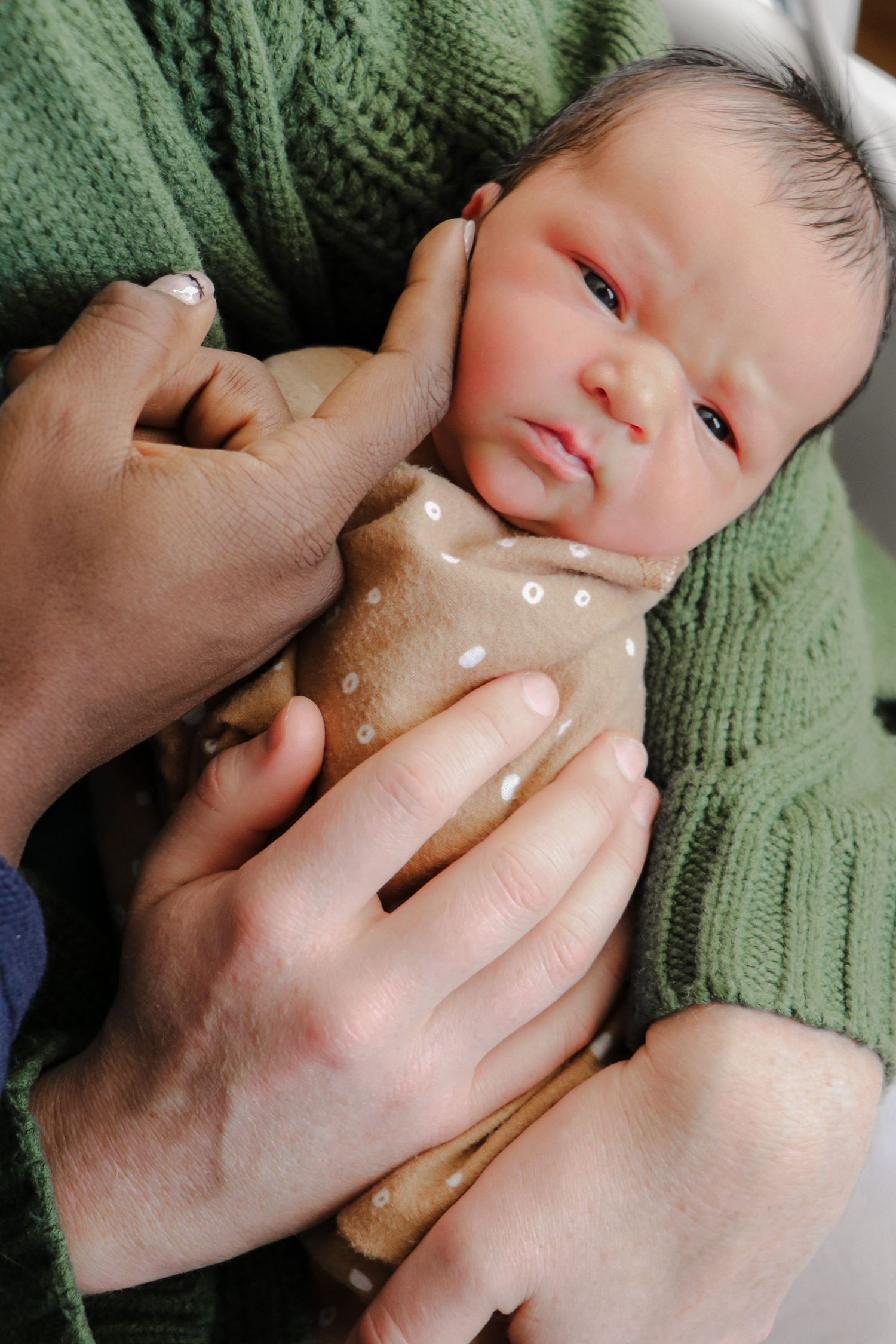 A series of images showing a baby receiving a gentle face massage with white cream or lotion being applied.