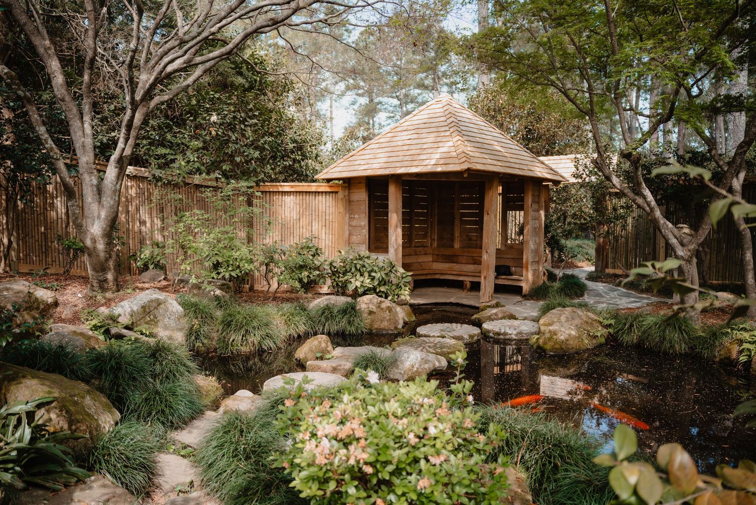 A cozy wooden cabin nestled in a lush garden with trees and plants surrounding it.